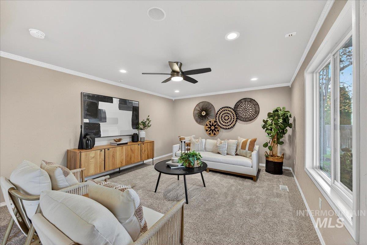 Carpeted living room with crown molding, recessed lighting, and a ceiling fan