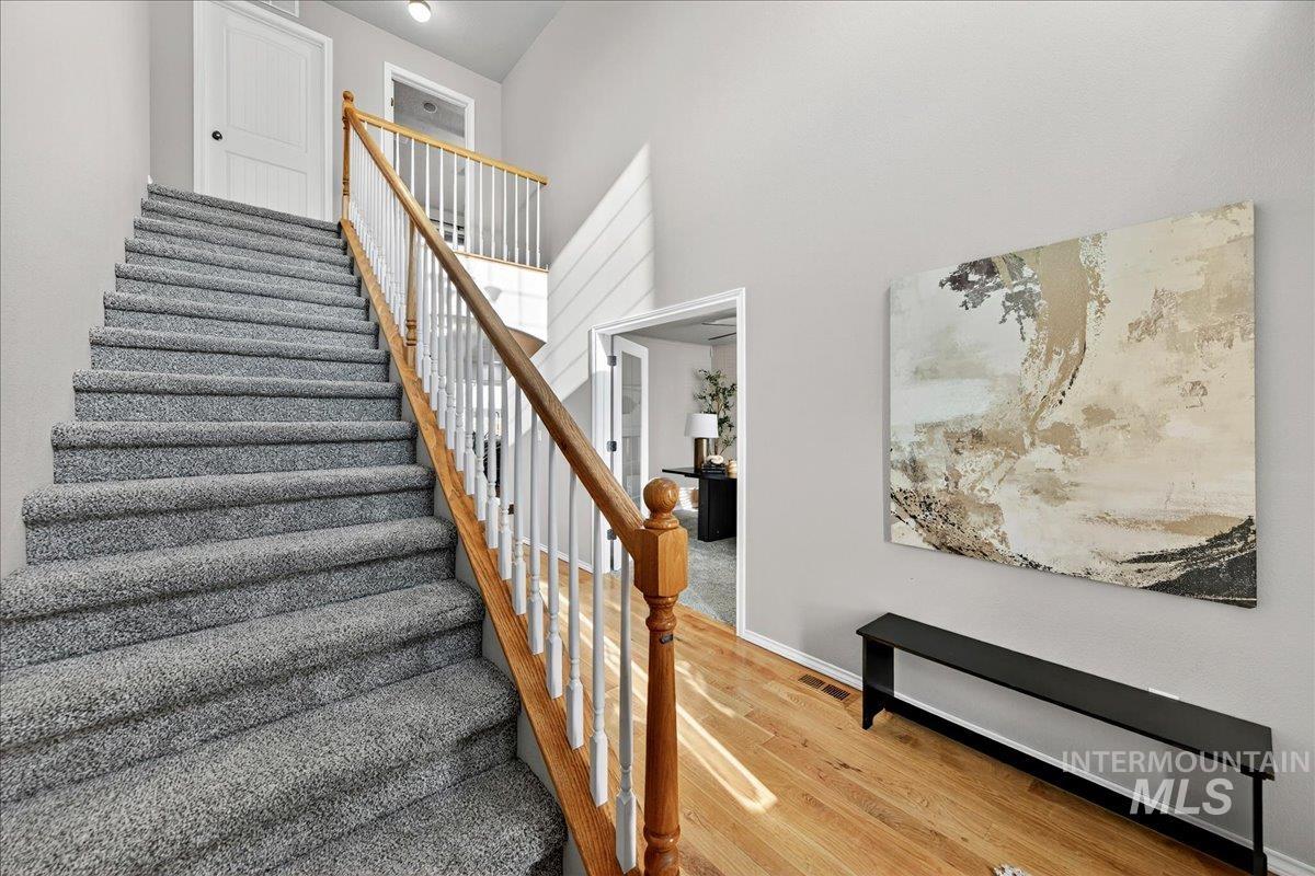 Staircase featuring wood finished floors and a high ceiling