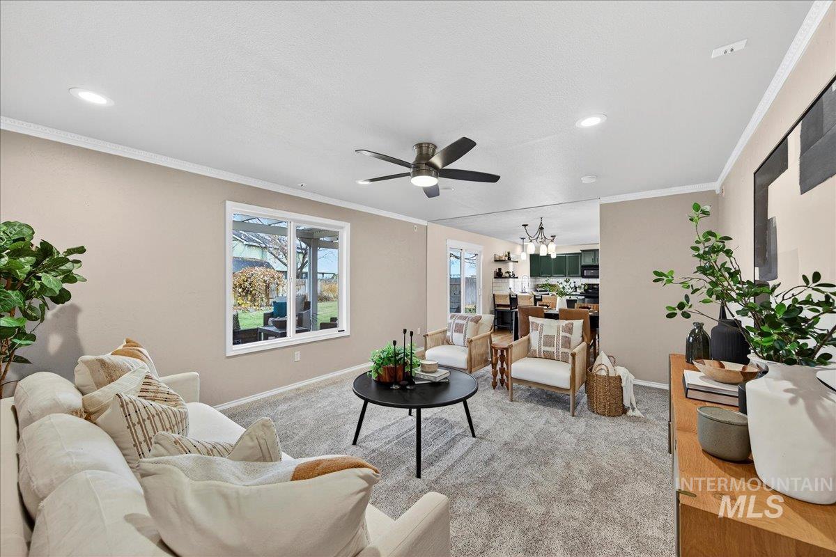 Living area featuring crown molding, ceiling fan, a chandelier, and recessed lighting