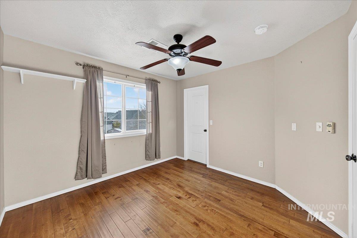 Empty room with wood-type flooring, a textured ceiling, and ceiling fan