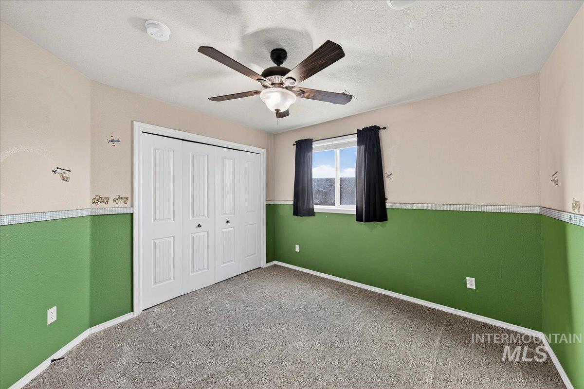 Unfurnished bedroom featuring carpet, a closet, ceiling fan, and a textured ceiling