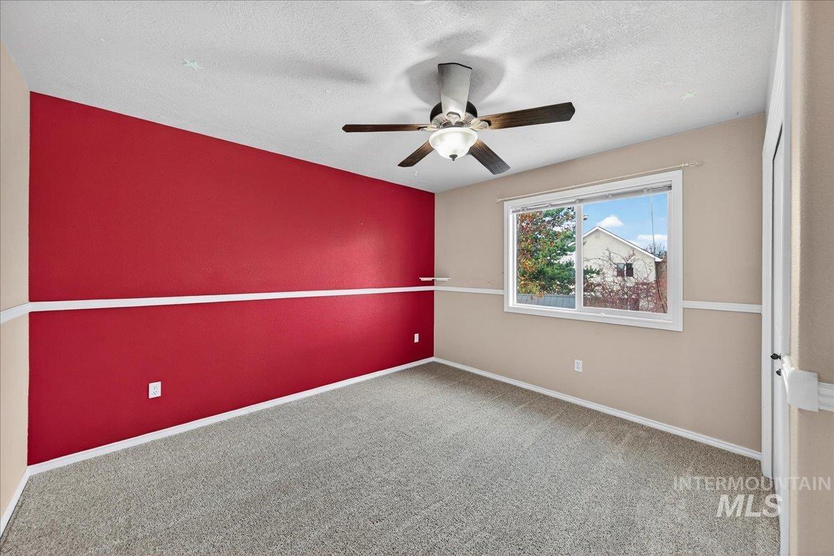 Empty room featuring carpet floors, ceiling fan, and a textured ceiling