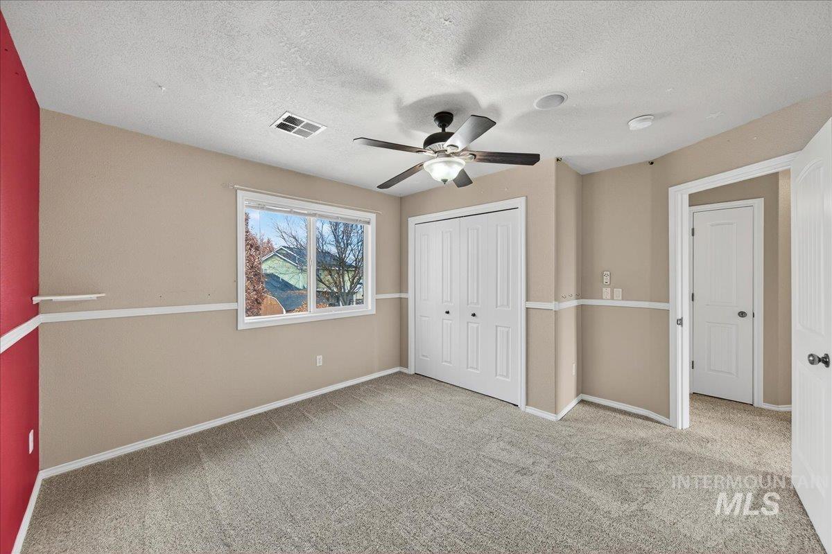 Unfurnished bedroom with light colored carpet, a textured ceiling, a ceiling fan, and a closet