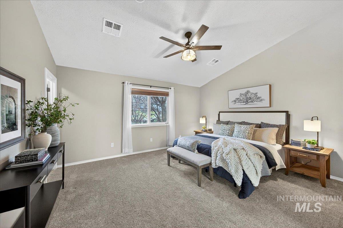 Carpeted bedroom featuring lofted ceiling, a textured ceiling, and ceiling fan