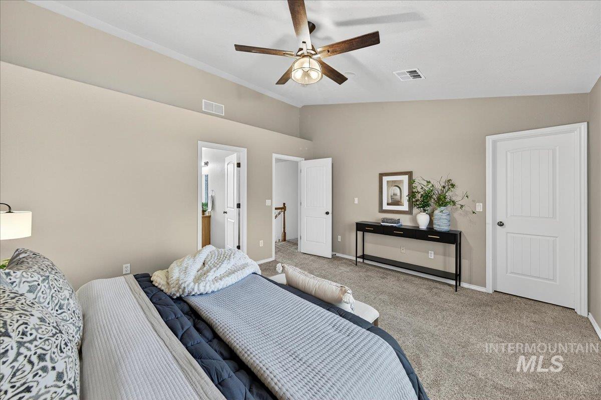 Carpeted bedroom featuring lofted ceiling, a ceiling fan, and connected bathroom