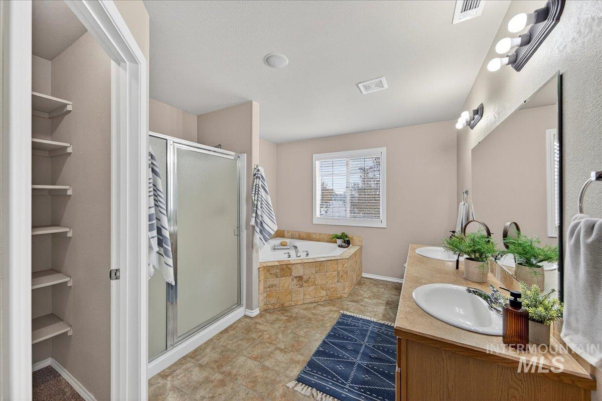 Bathroom with a garden tub, double vanity, a stall shower, and light tile patterned flooring