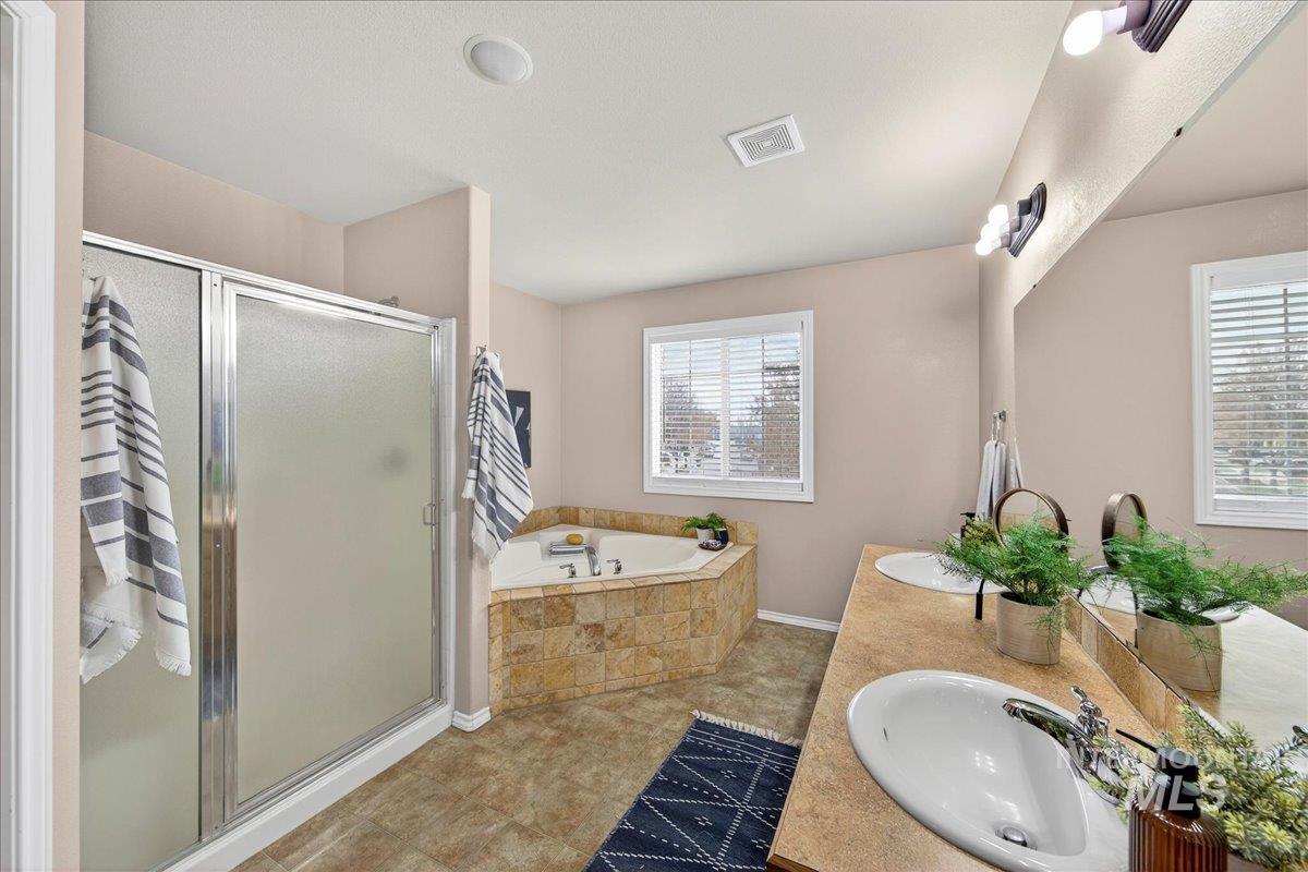 Bathroom with double vanity, a bath, a shower stall, and tile patterned flooring