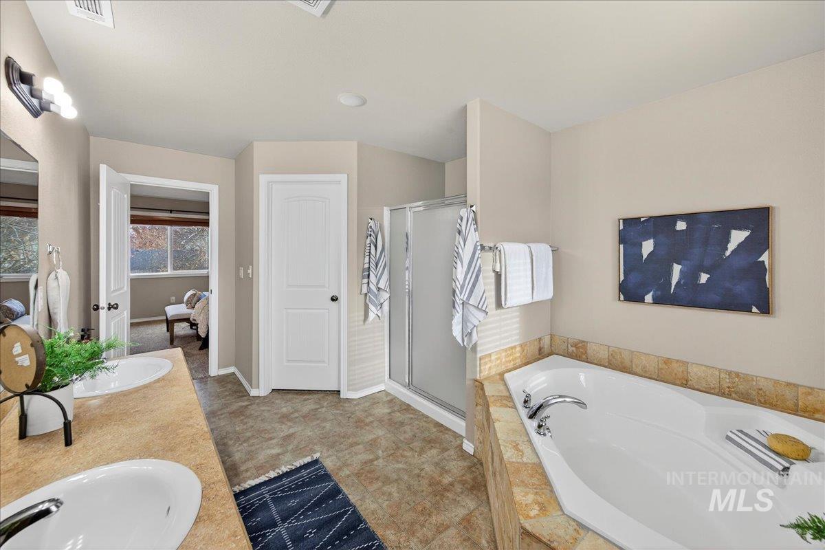 Full bath with a garden tub, double vanity, a stall shower, and connected bathroom