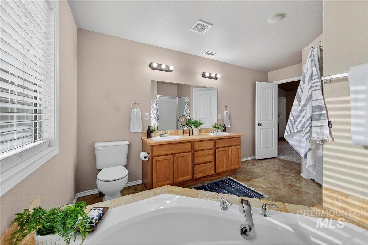 Bathroom with a bath, double vanity, and a shower stall