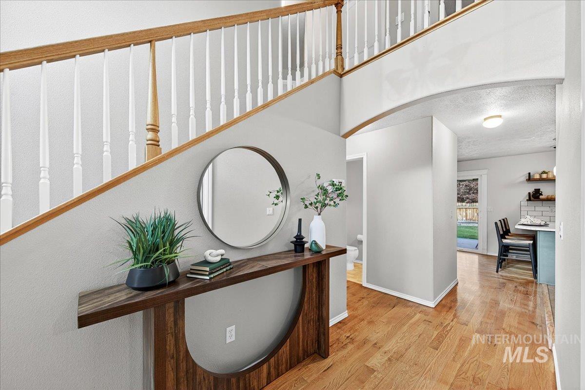 Corridor featuring wood finished floors, arched walkways, and a textured ceiling