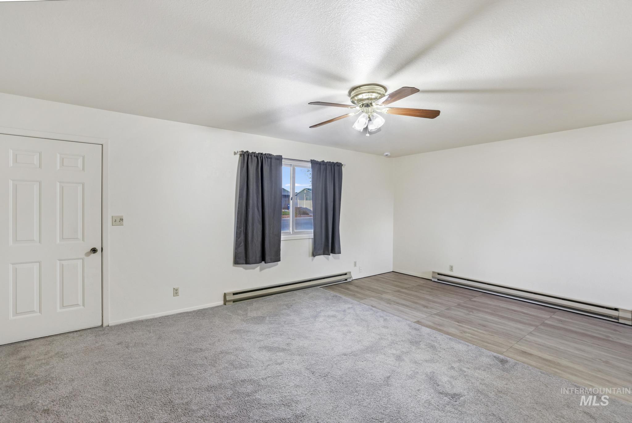 Spare room with a baseboard radiator, light carpet, and ceiling fan