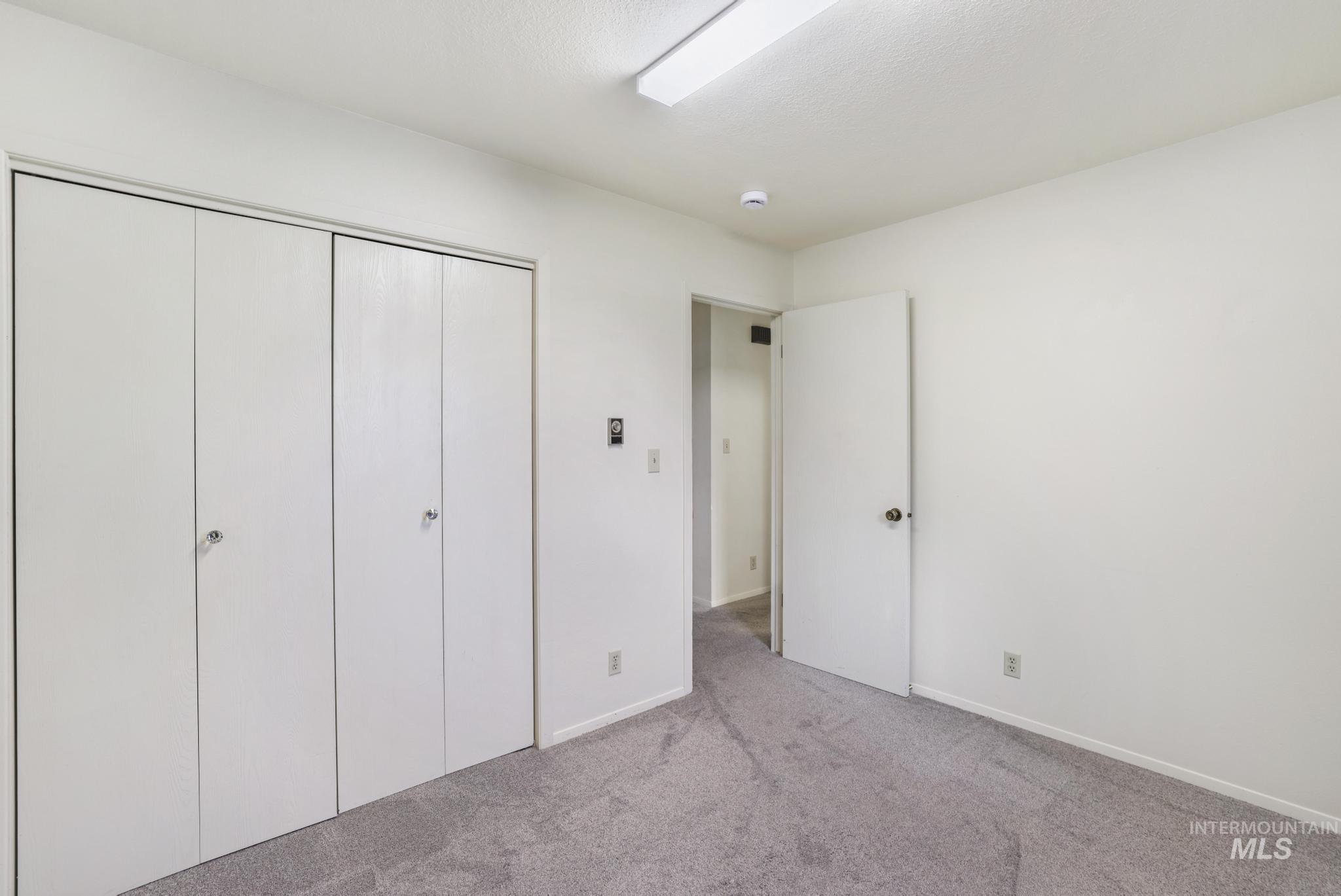 Unfurnished bedroom featuring light carpet and a closet