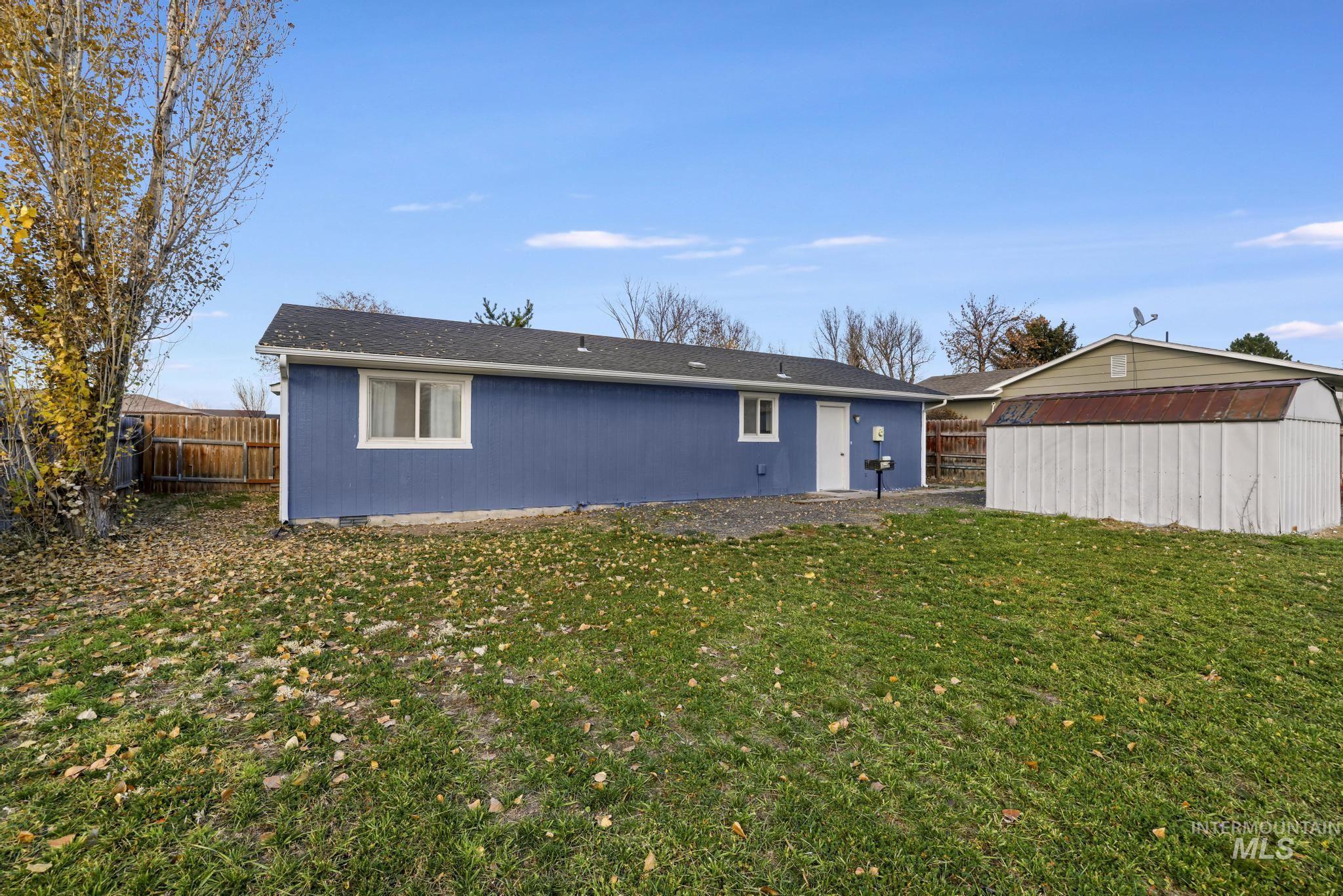 Rear view of house featuring a fenced backyard and a storage unit