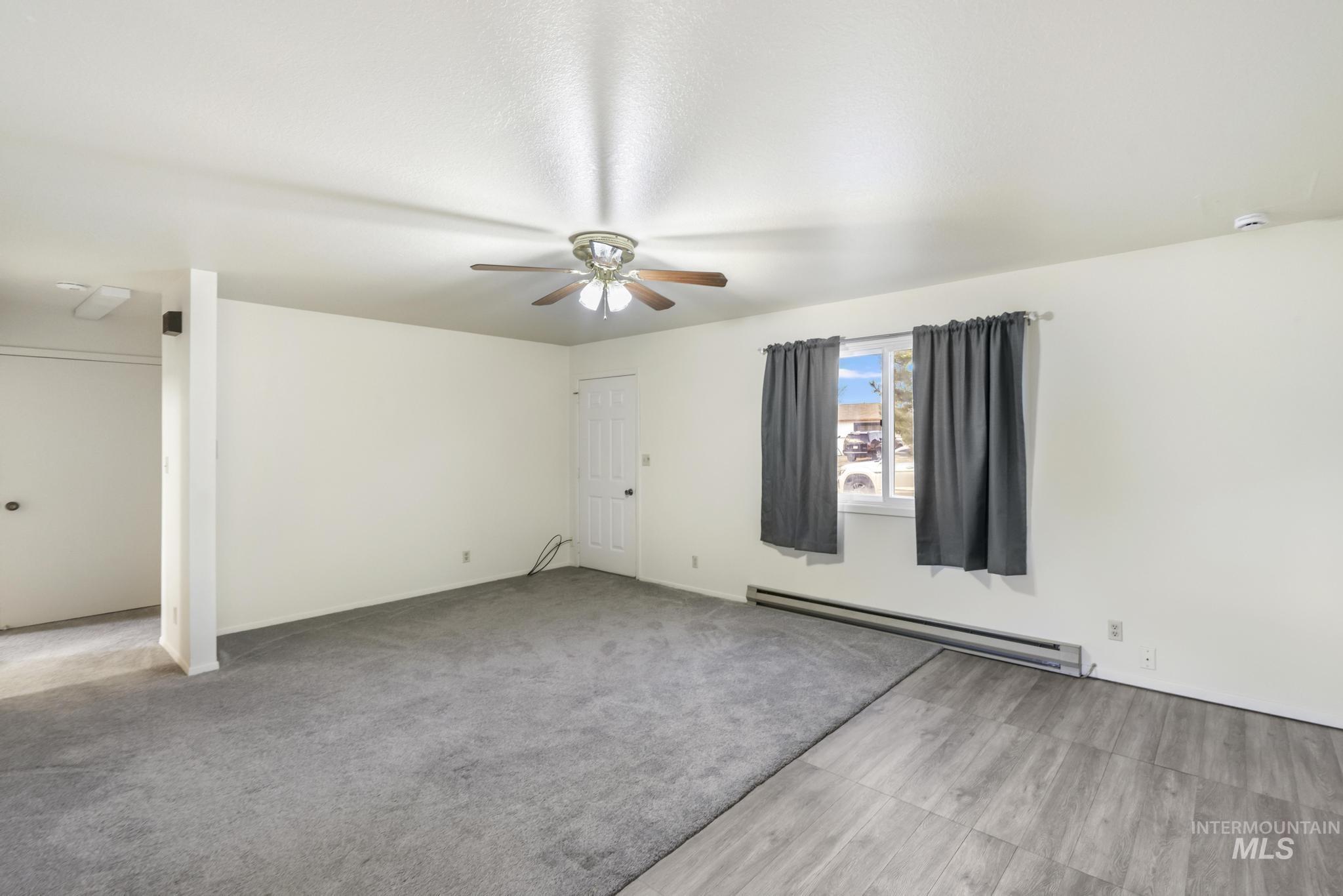 Unfurnished room featuring baseboard heating, light carpet, and ceiling fan
