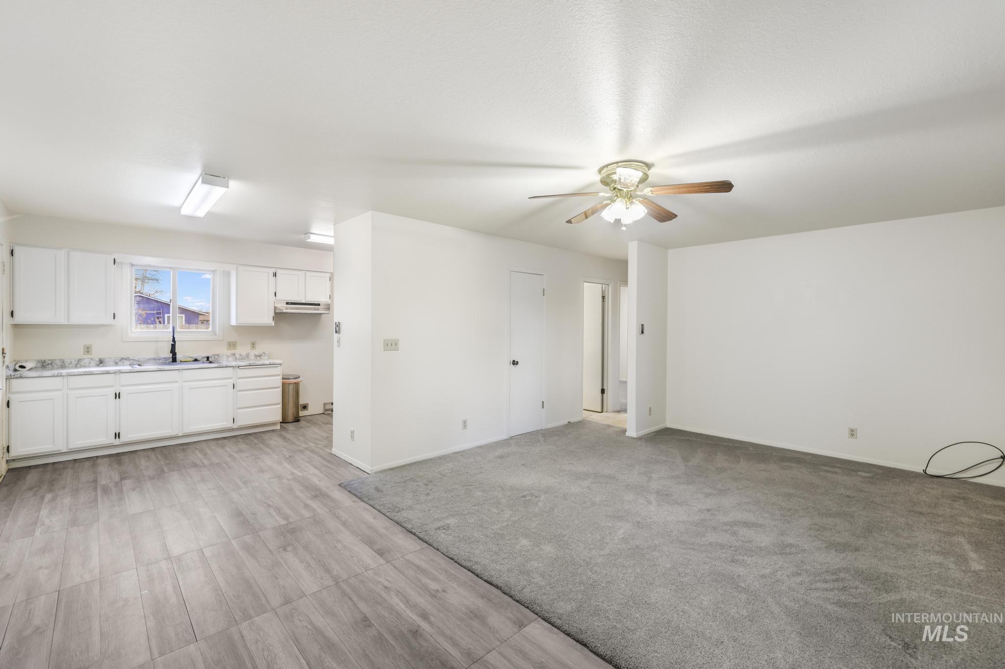 Unfurnished living room featuring a ceiling fan and light colored carpet