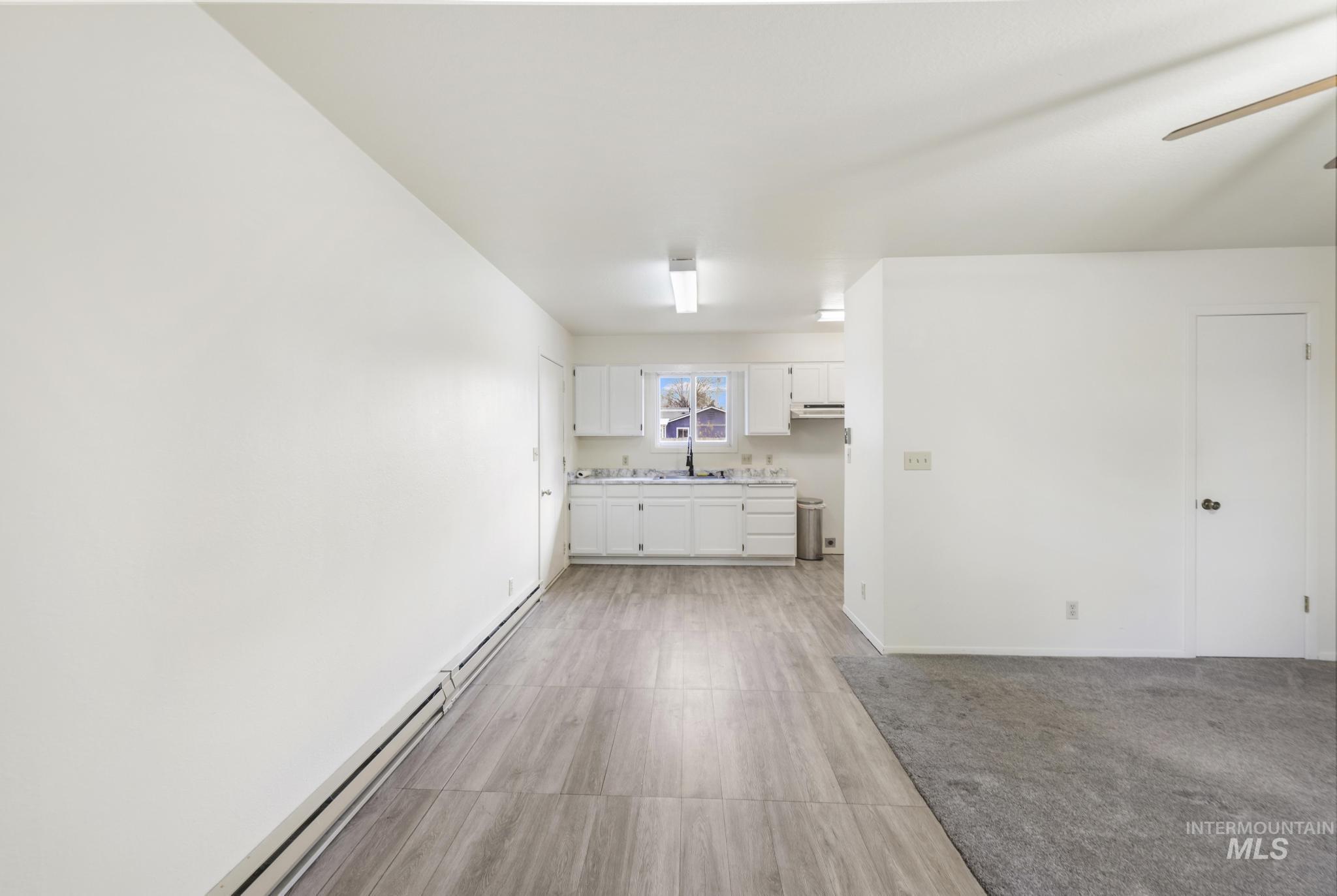 Unfurnished living room featuring a baseboard radiator and a ceiling fan