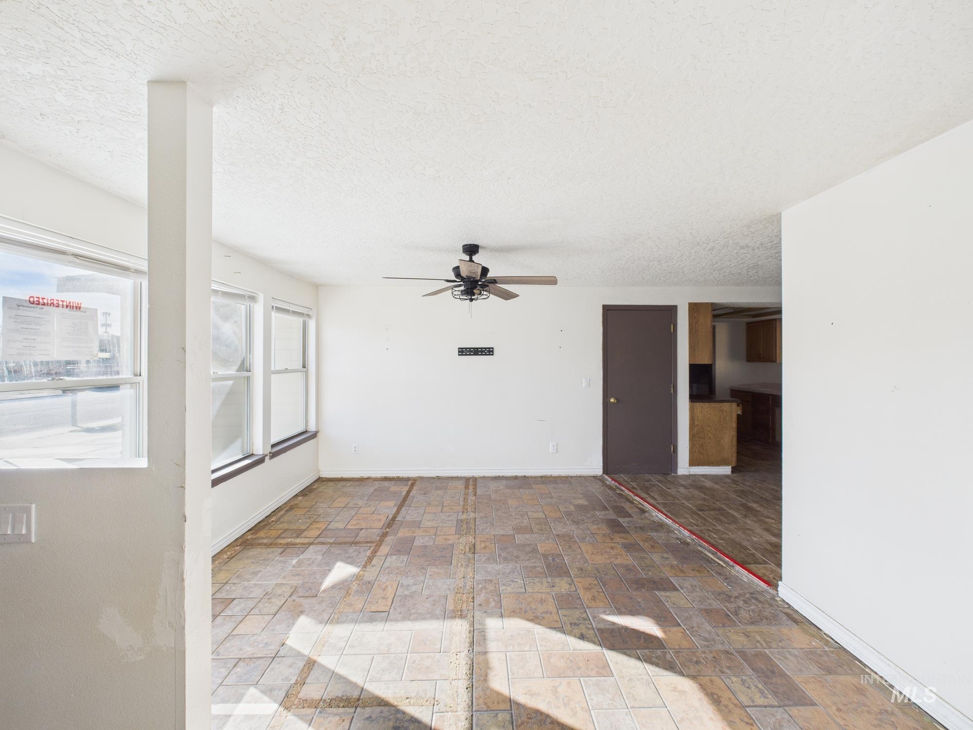 Spare room featuring ceiling fan, stone tile floors, and a textured ceiling