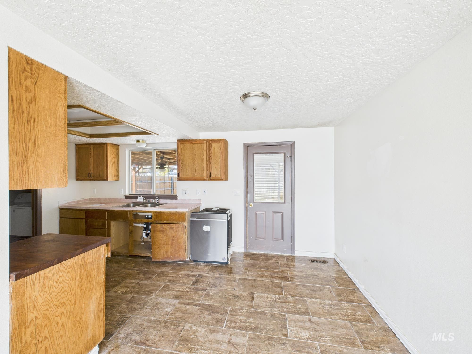 Kitchen with brown cabinets and a textured ceiling