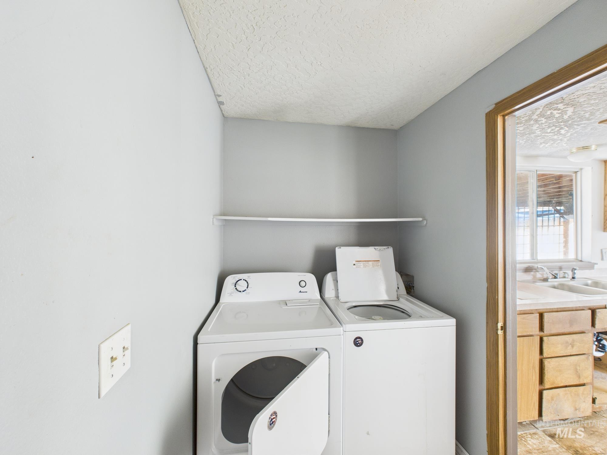 Washroom featuring a textured ceiling and washer and clothes dryer