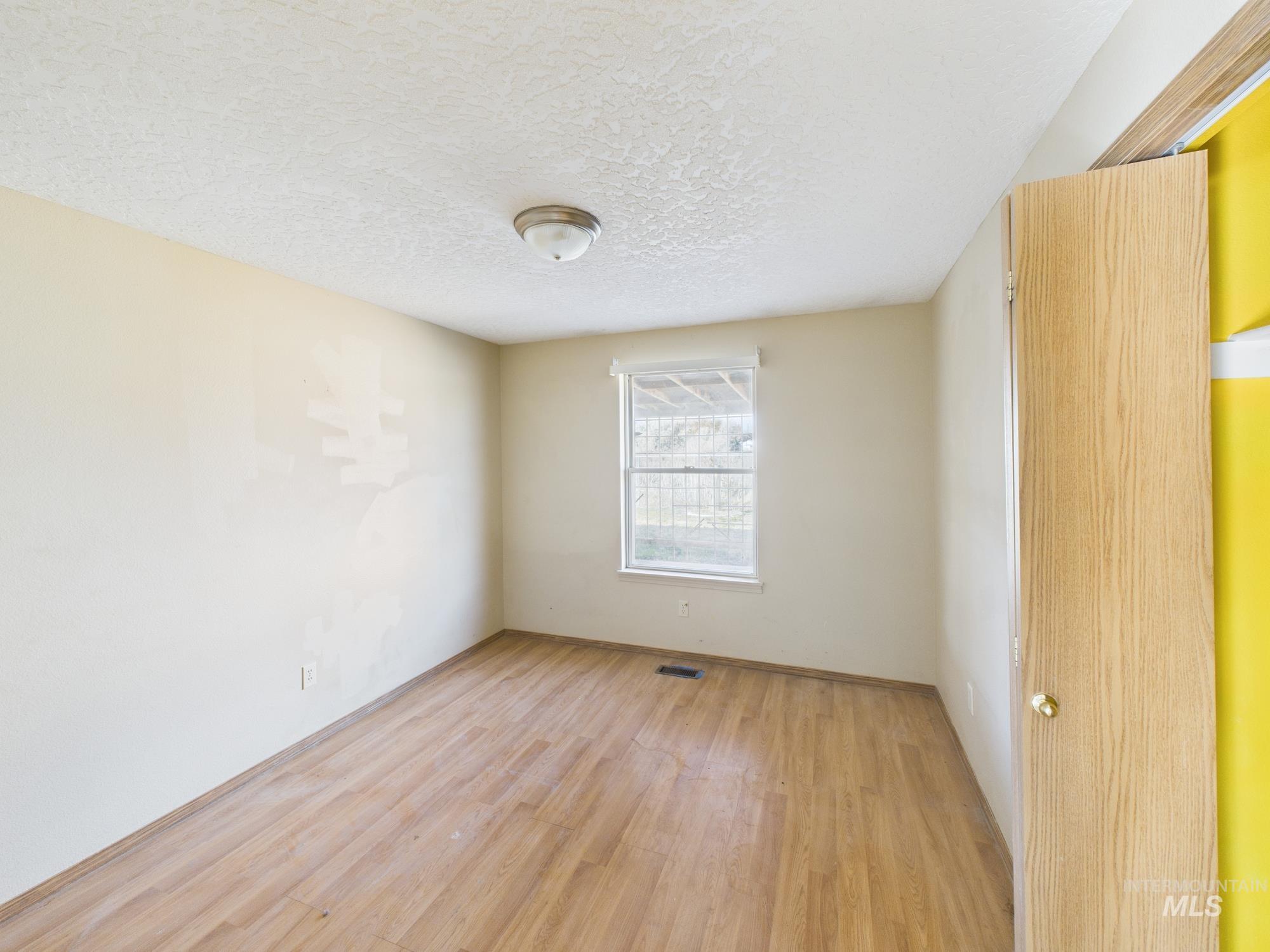 Spare room with light wood-style floors and a textured ceiling