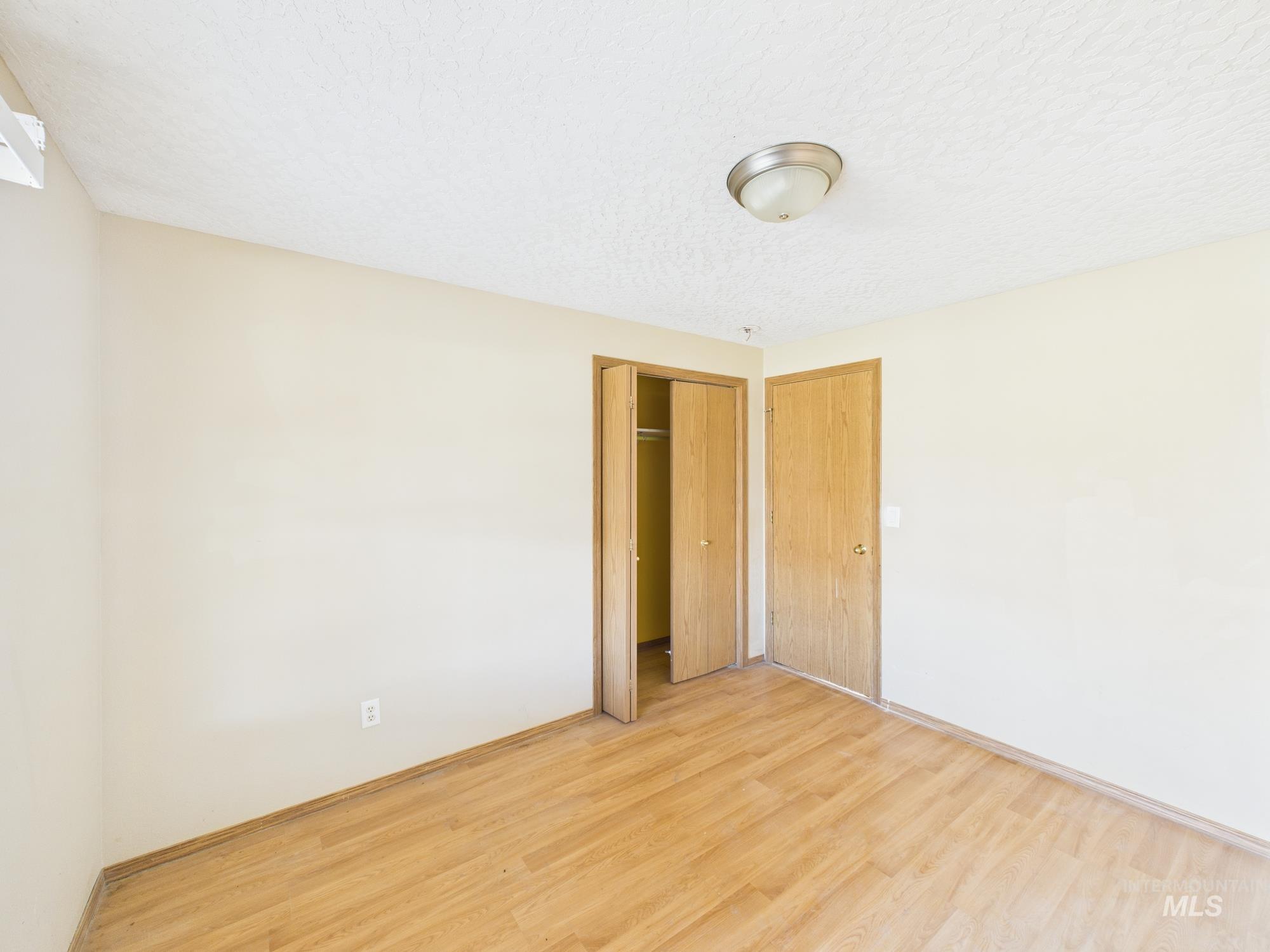 Unfurnished bedroom featuring wood finished floors, a closet, and a textured ceiling
