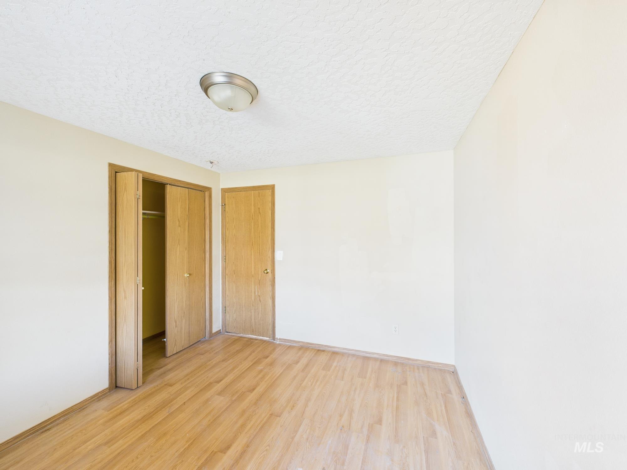 Unfurnished bedroom featuring light wood finished floors, a closet, and a textured ceiling