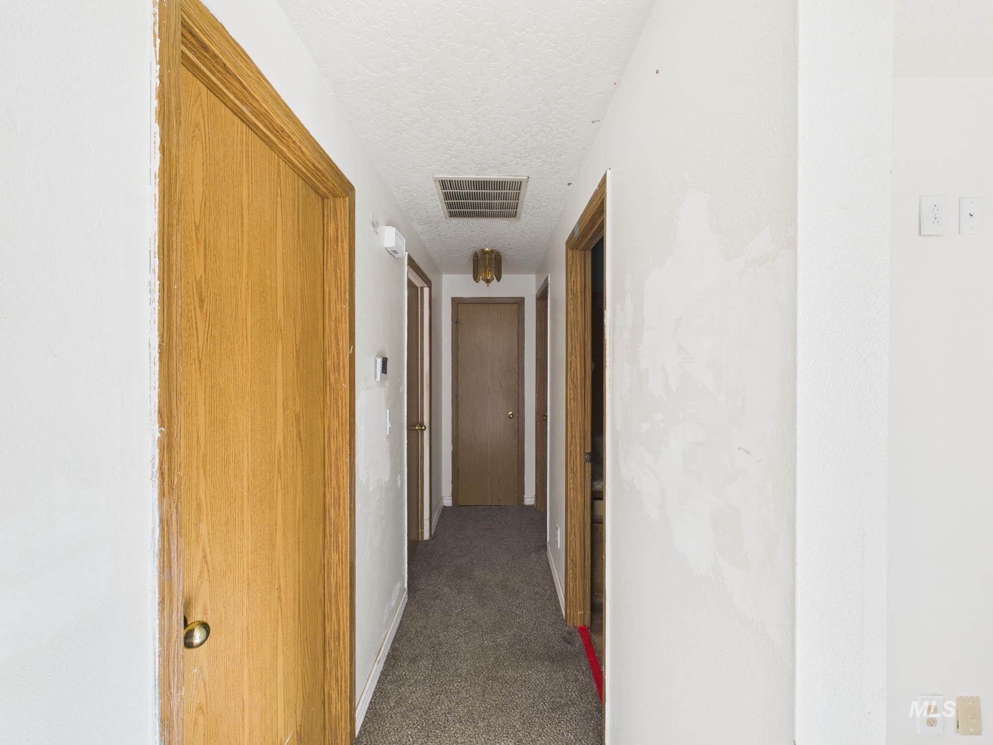 Hall with dark colored carpet and a textured ceiling