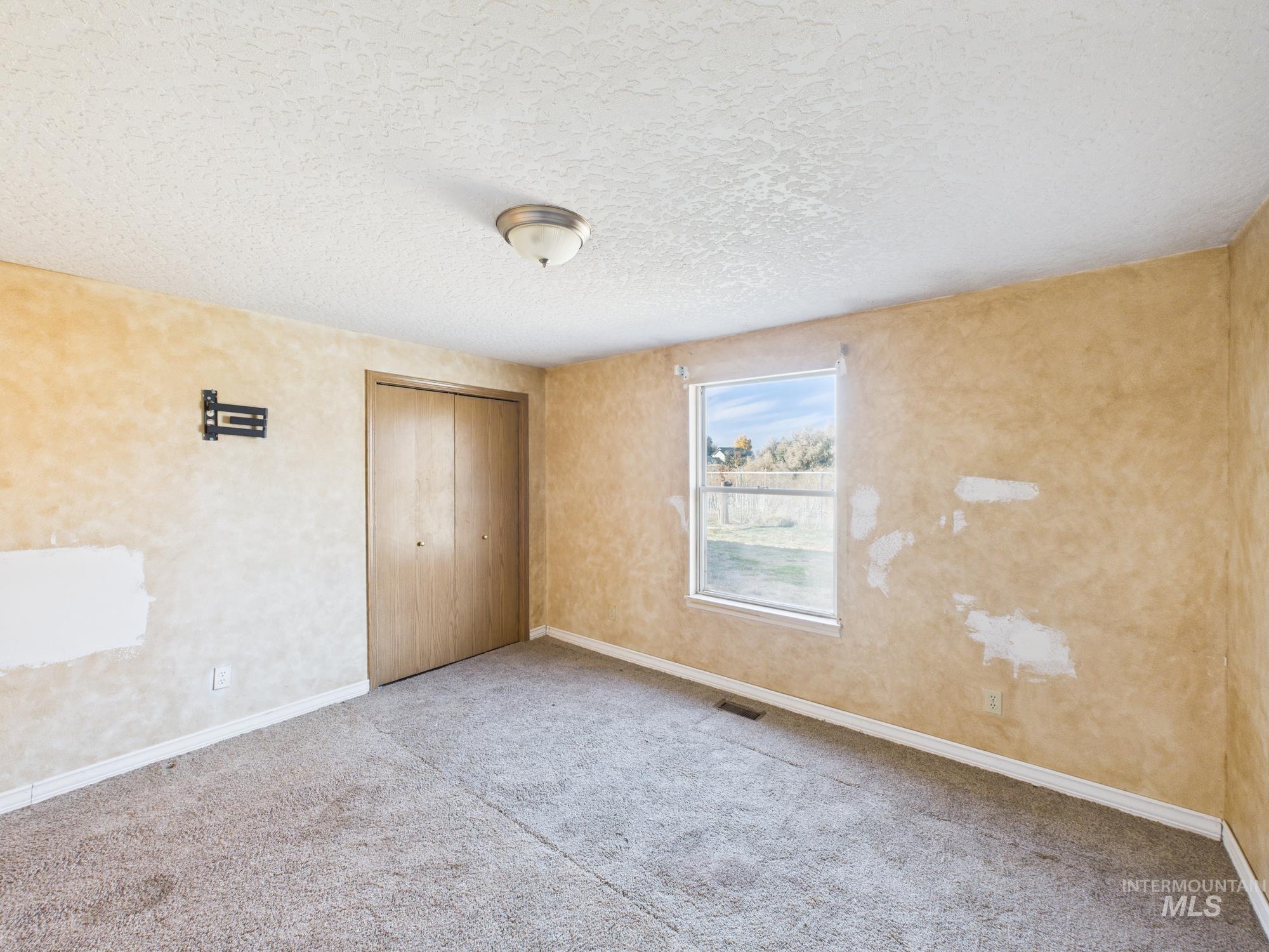 Unfurnished bedroom with a closet, a textured ceiling, and carpet flooring