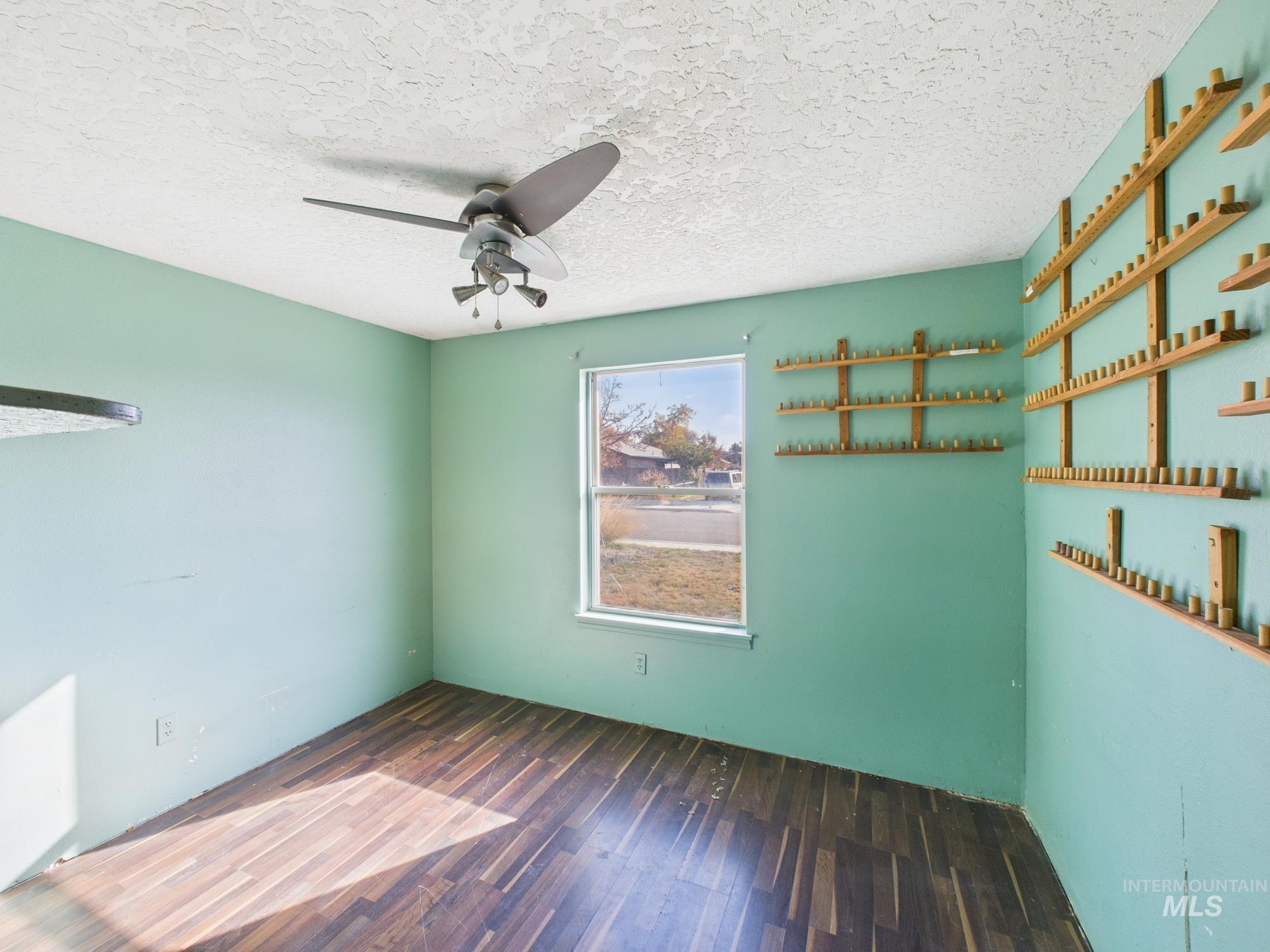 Spare room with wood finished floors, a textured ceiling, and a ceiling fan