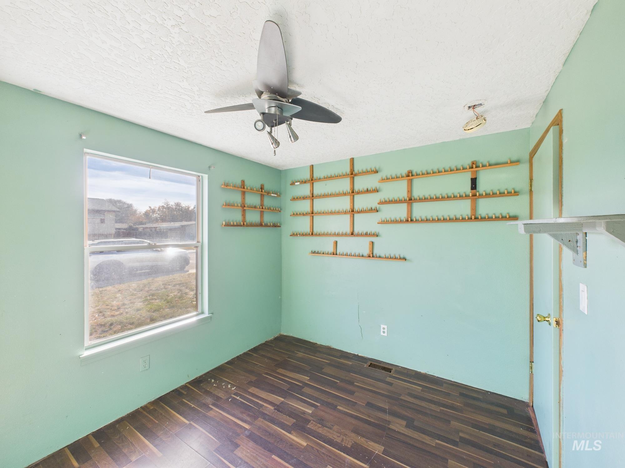Empty room featuring dark wood-style flooring, ceiling fan, and a textured ceiling