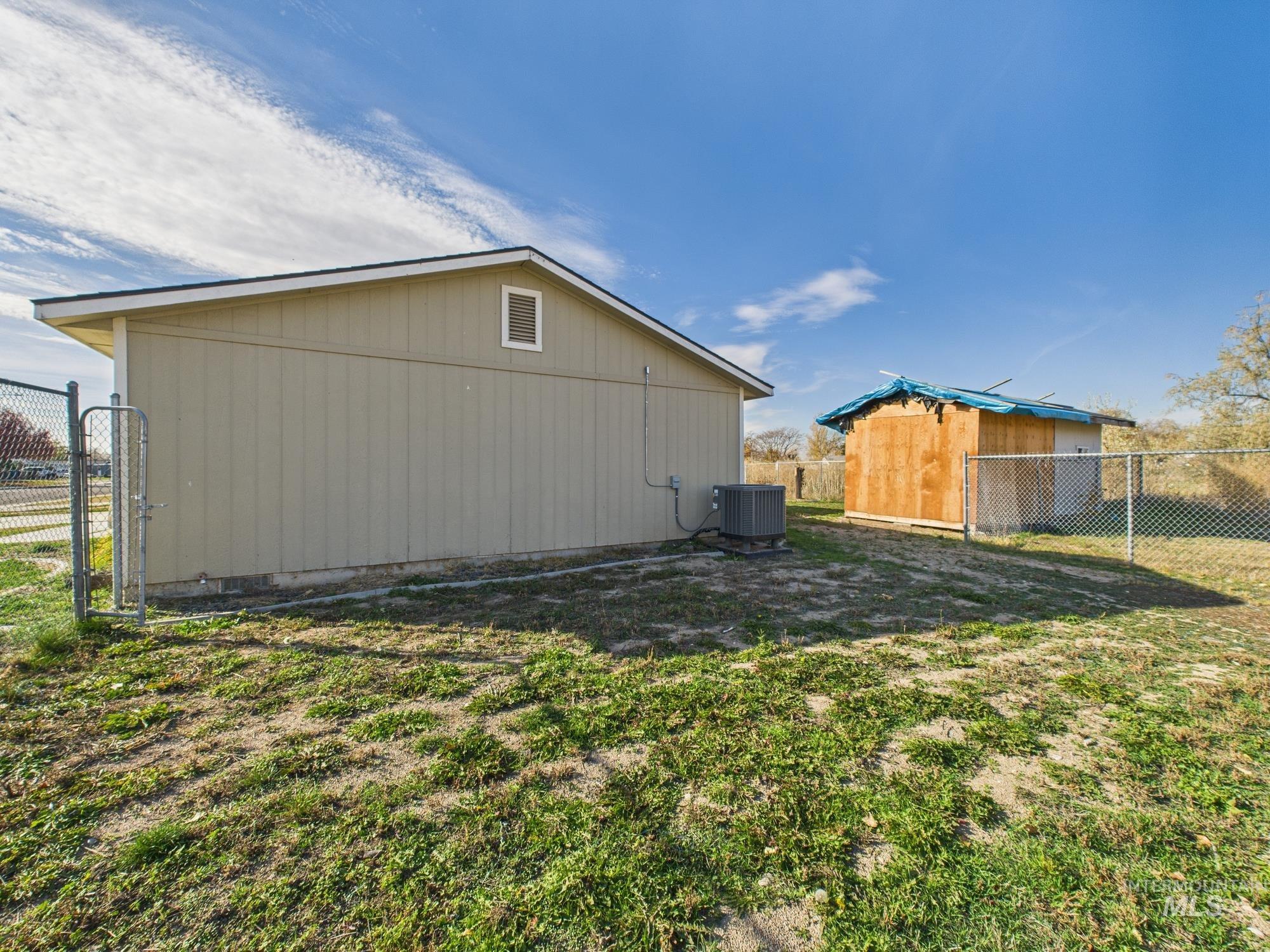 View of side of home with a fenced backyard, an outbuilding, and a gate
