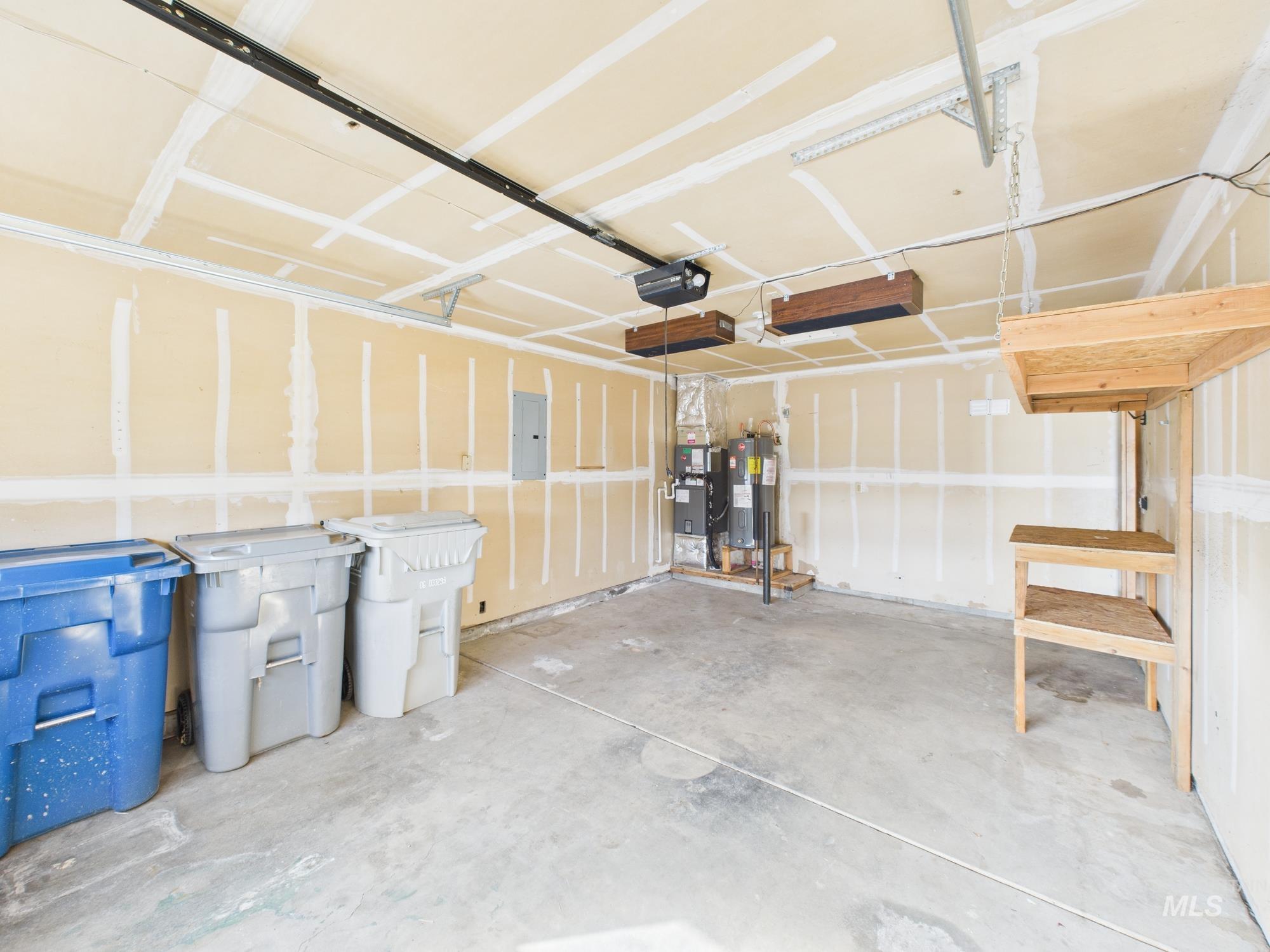 Garage with electric panel, water heater, and a garage door opener
