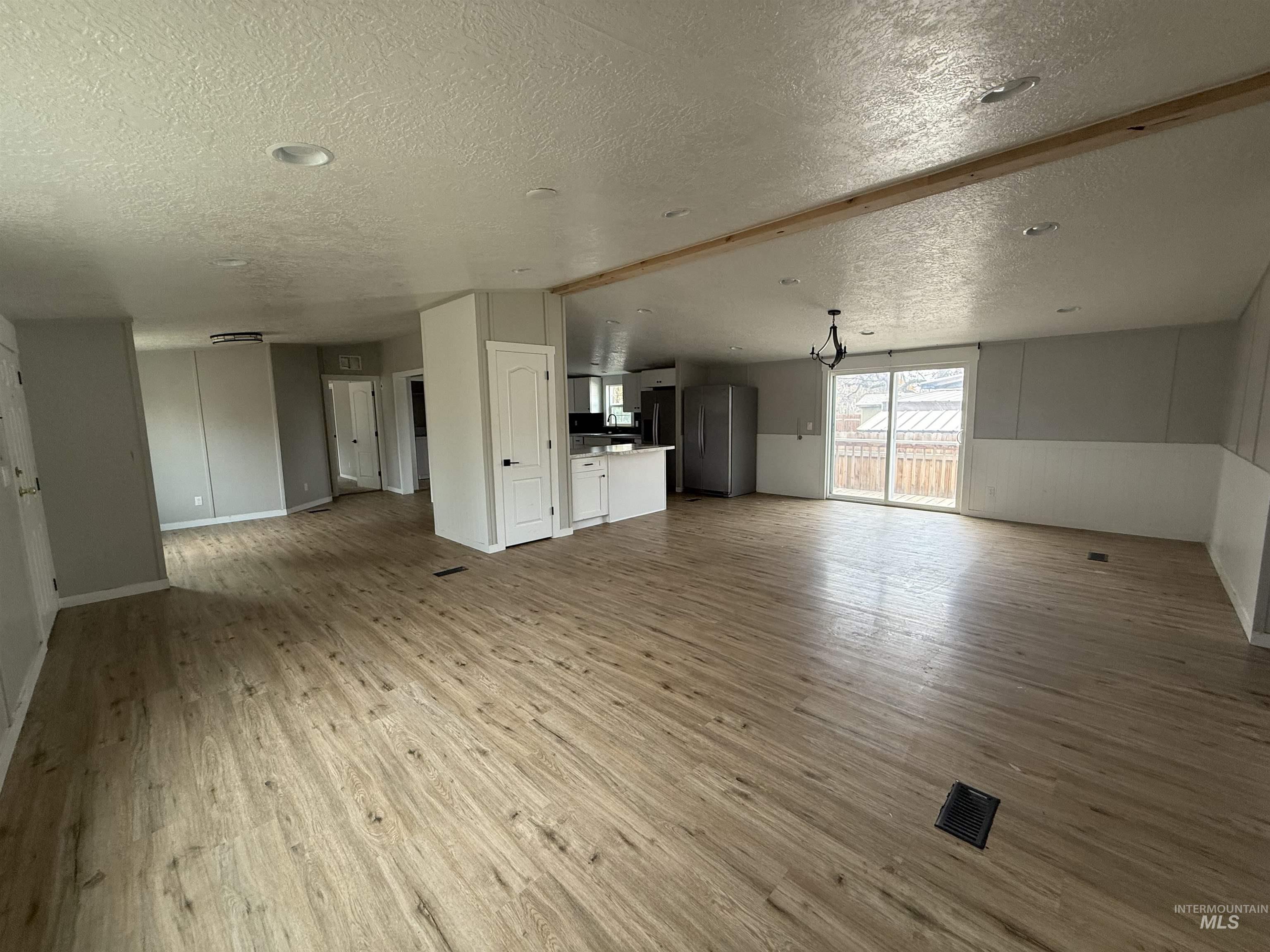 Unfurnished living room featuring light wood finished floors, a textured ceiling, and lofted ceiling