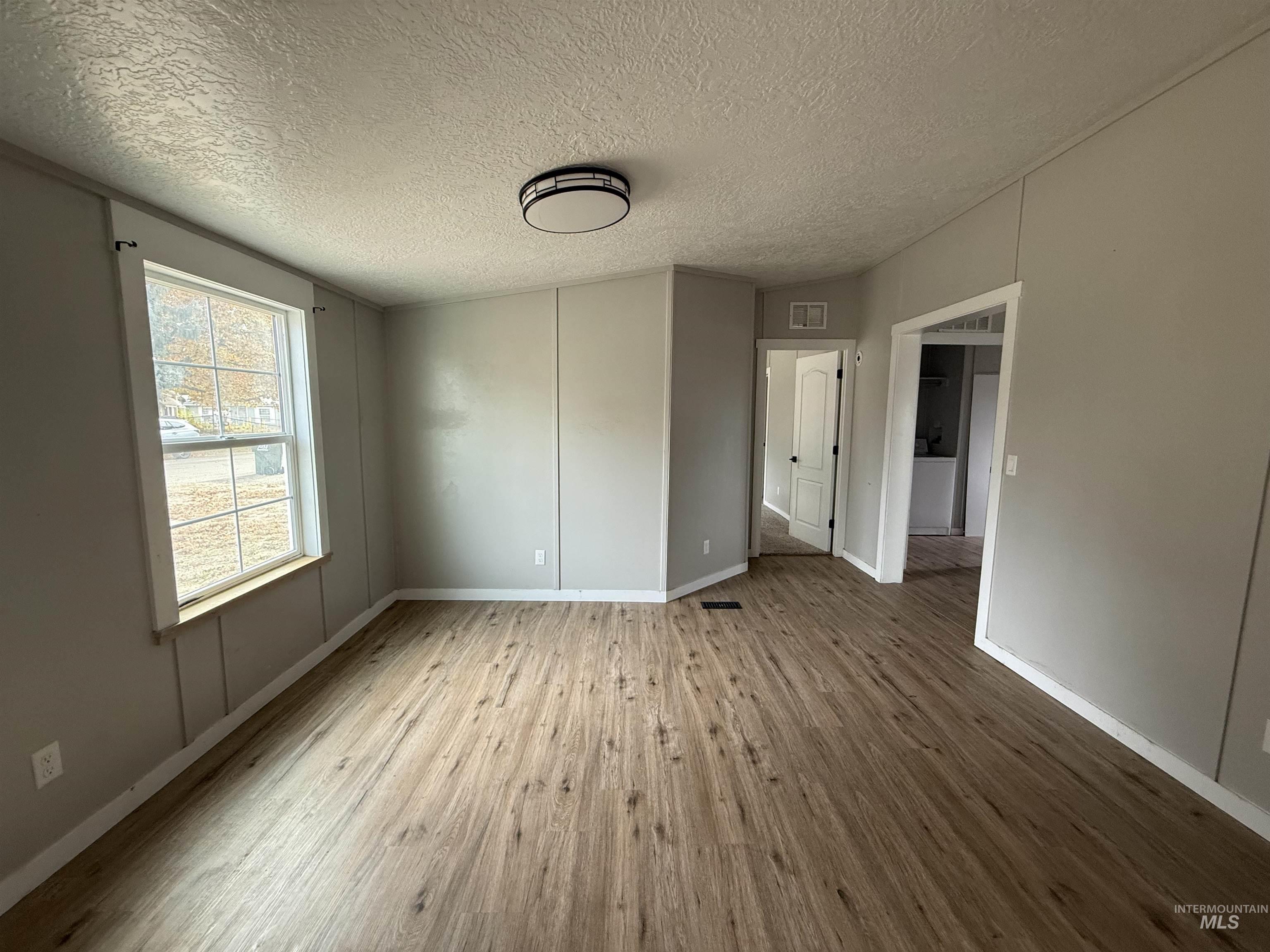 Unfurnished room featuring a textured ceiling and light wood-type flooring
