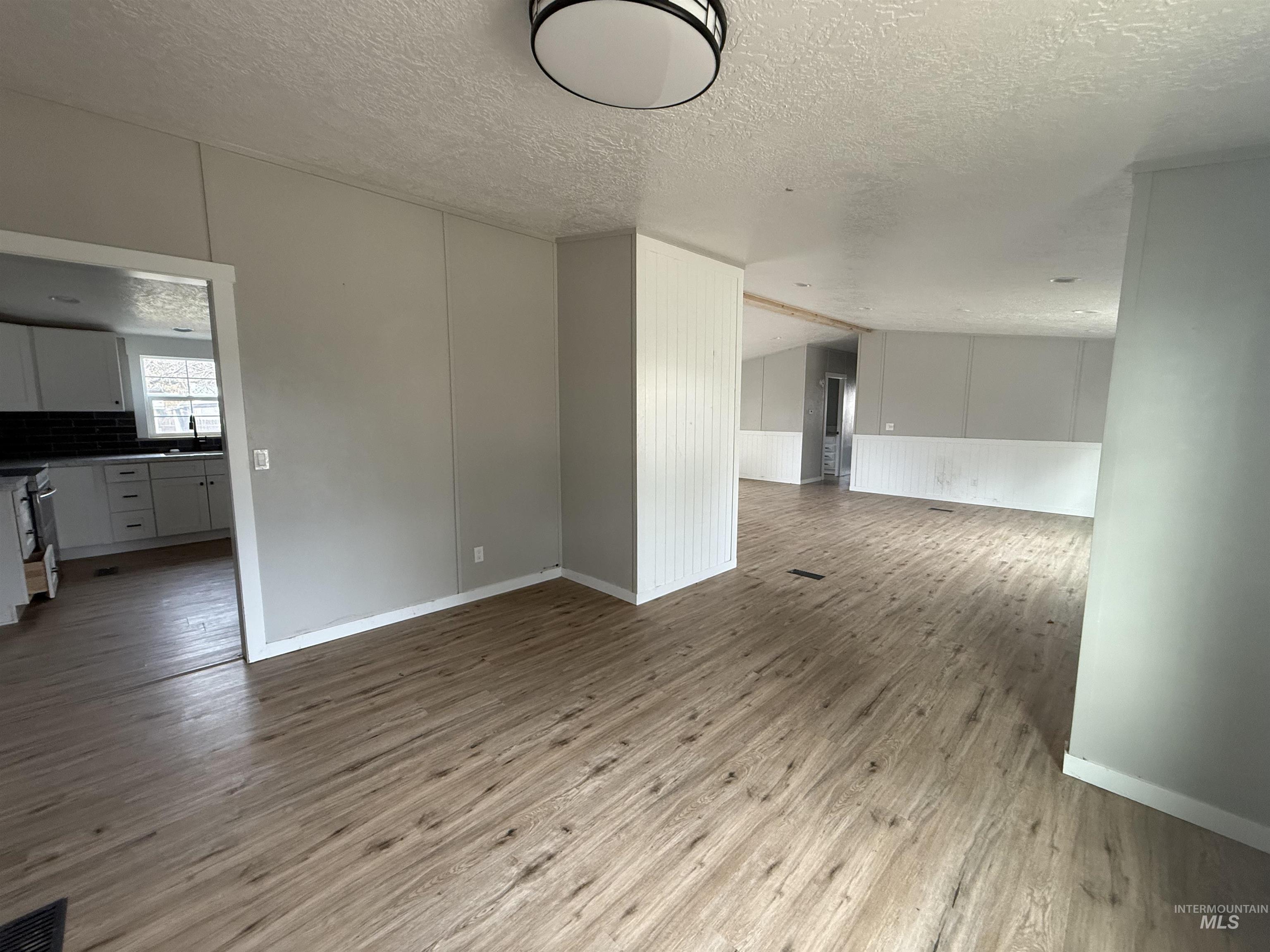 Unfurnished living room with wood finished floors and a textured ceiling