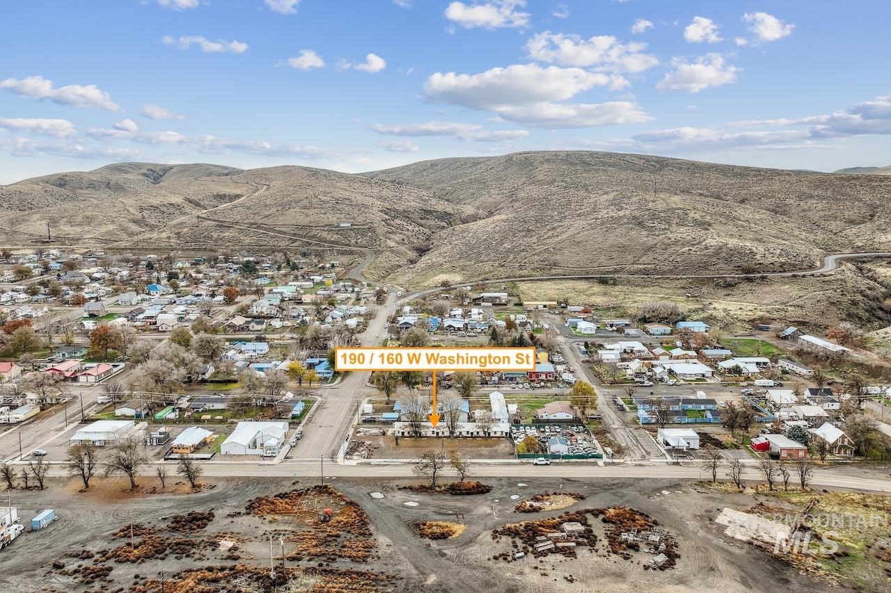 Aerial view of property and surrounding area with a mountainous background and nearby suburban area