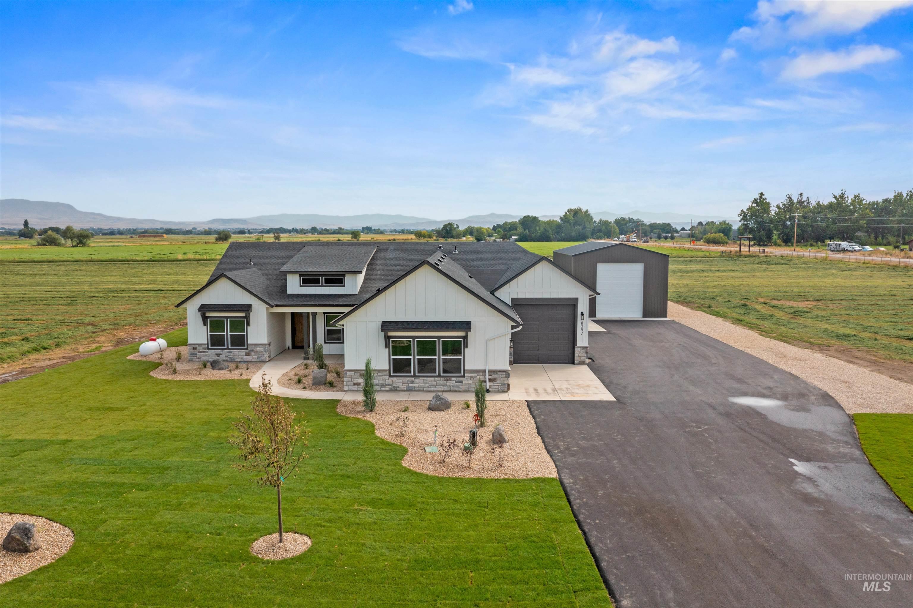 Modern inspired farmhouse with stone siding, a front lawn, driveway, covered porch, and board and batten siding
