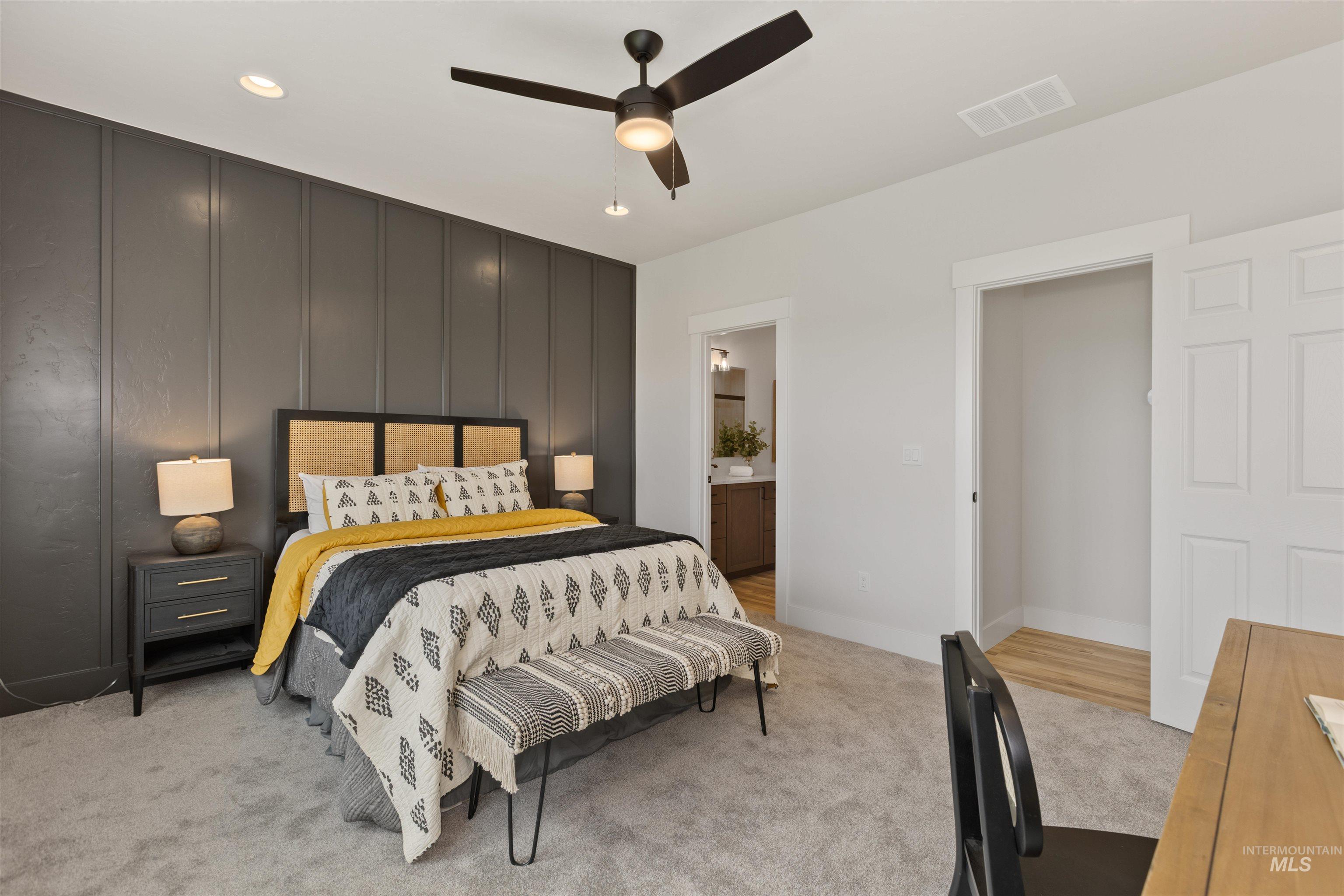 Bedroom featuring light carpet, ensuite bathroom, ceiling fan, recessed lighting, and a decorative wall