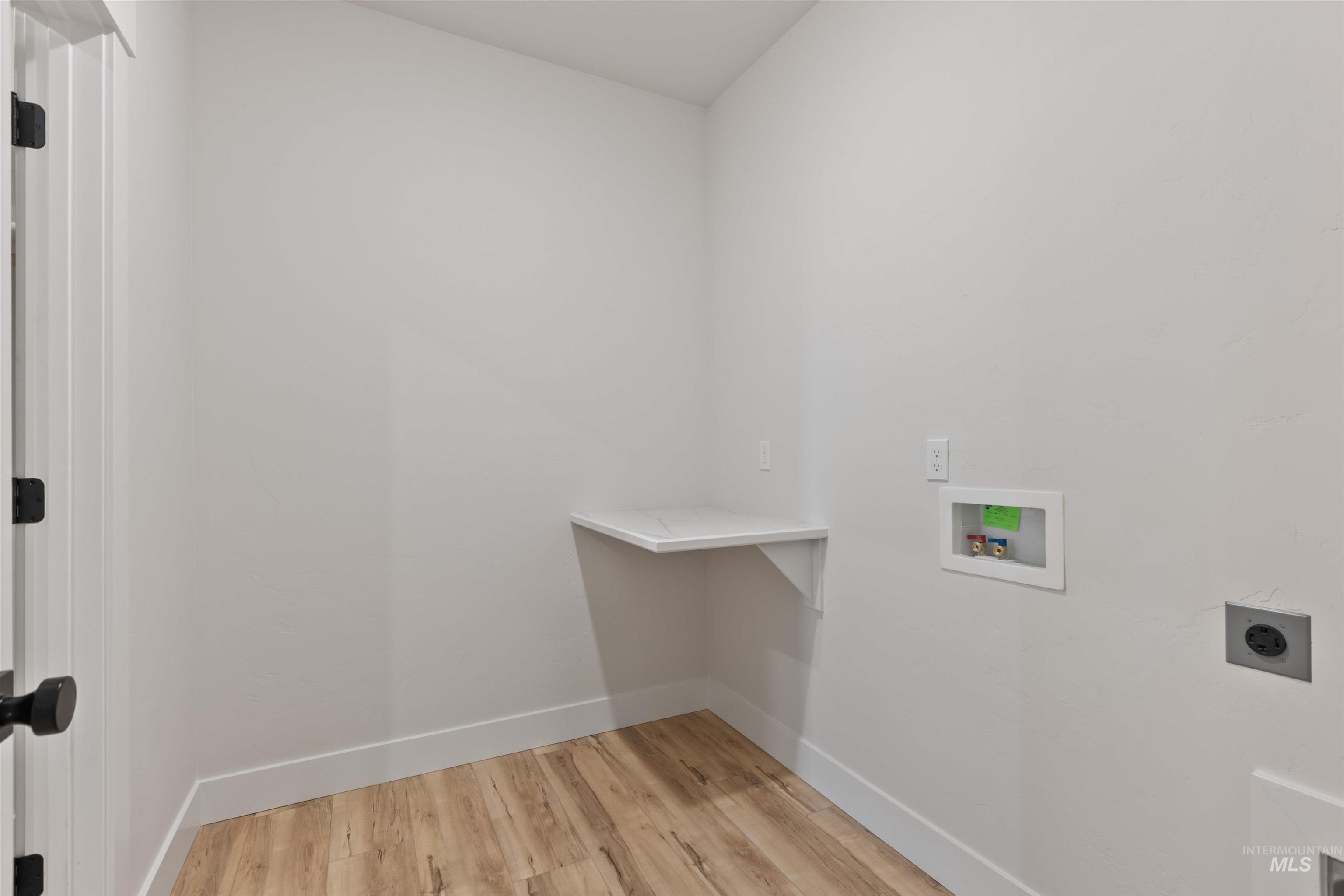Laundry area with light wood-type flooring, washer hookup, and hookup for an electric dryer
