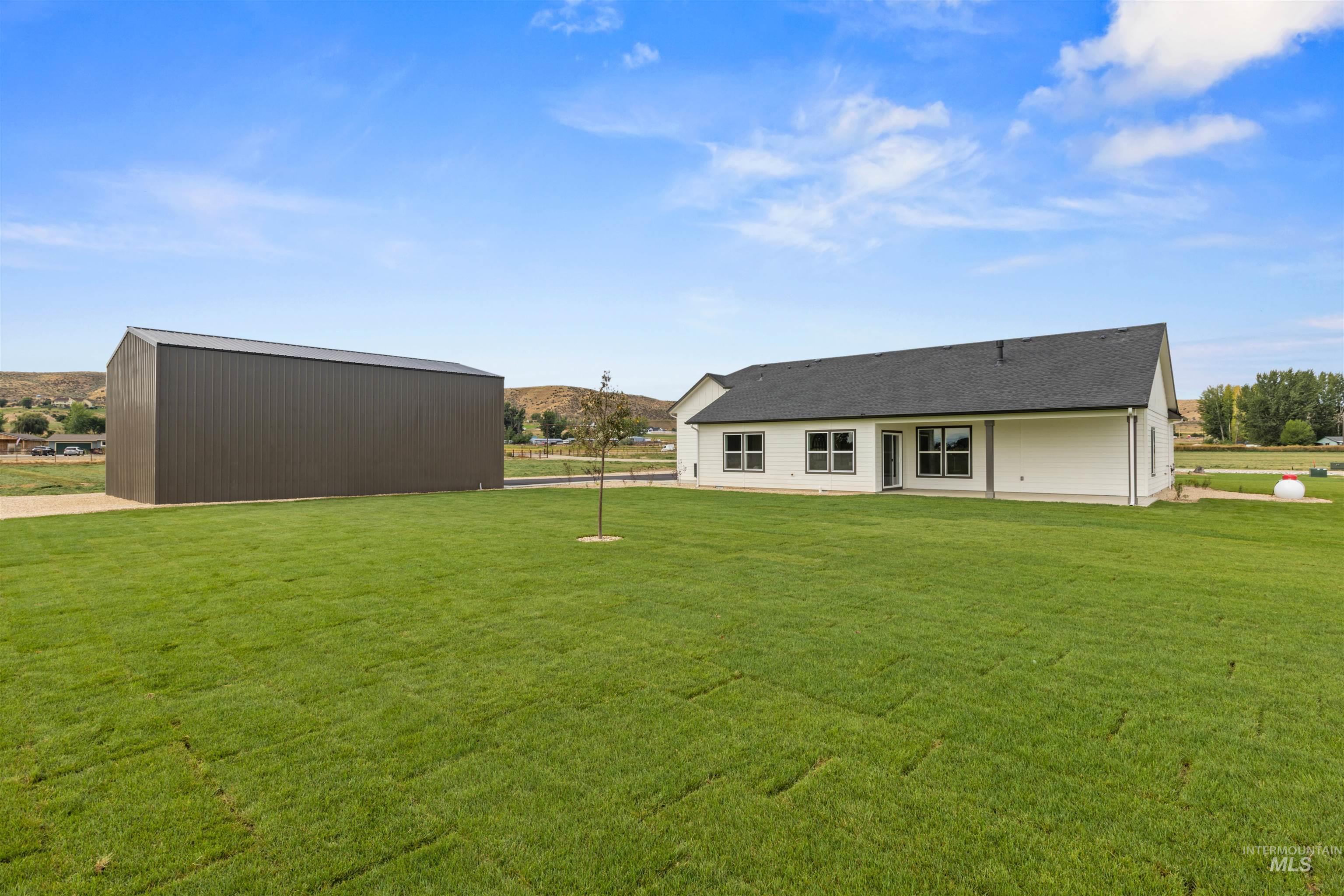Rear view of house featuring a mountain view, a lawn, and an outdoor structure