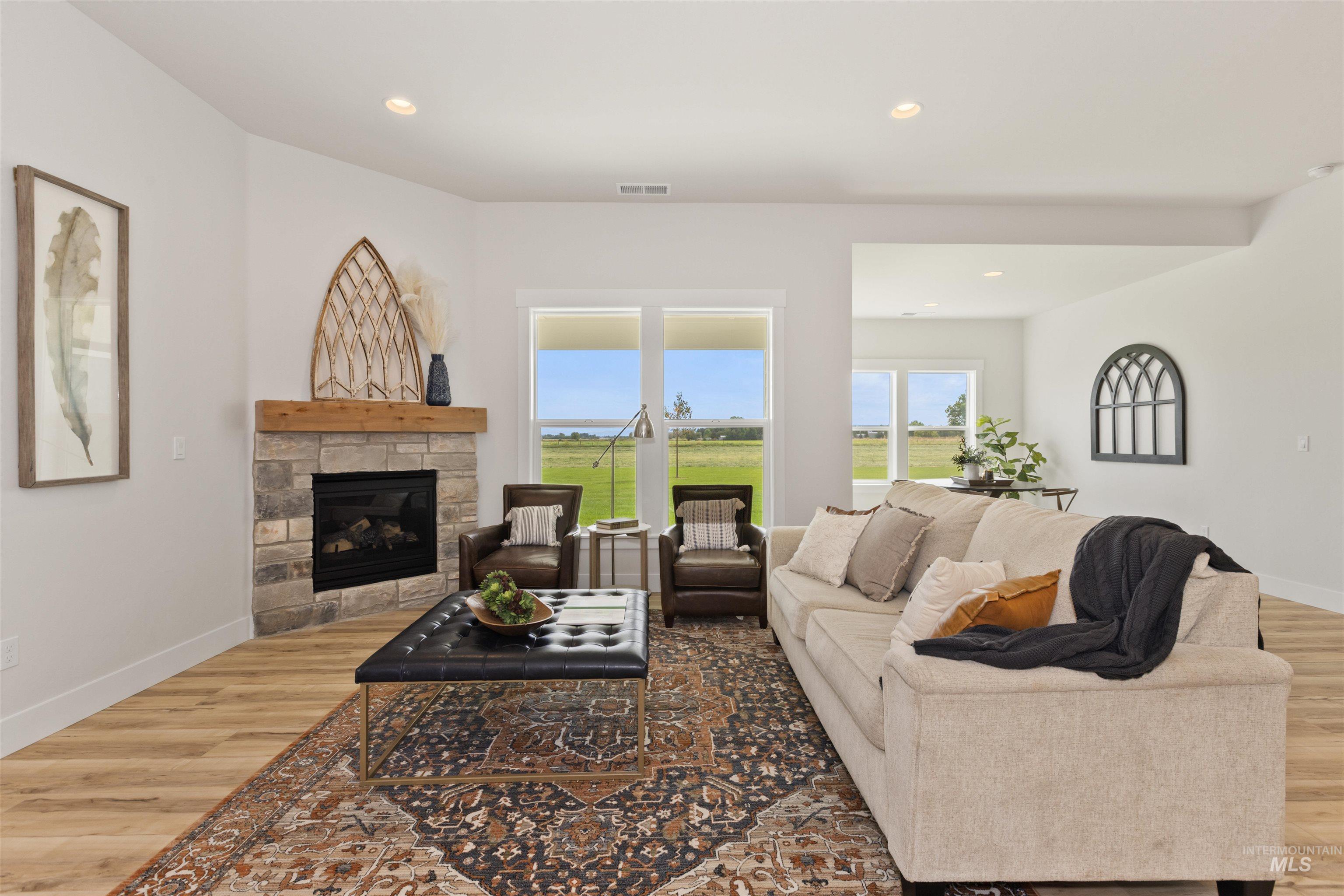 Living area featuring light wood-style floors, recessed lighting, and a stone fireplace