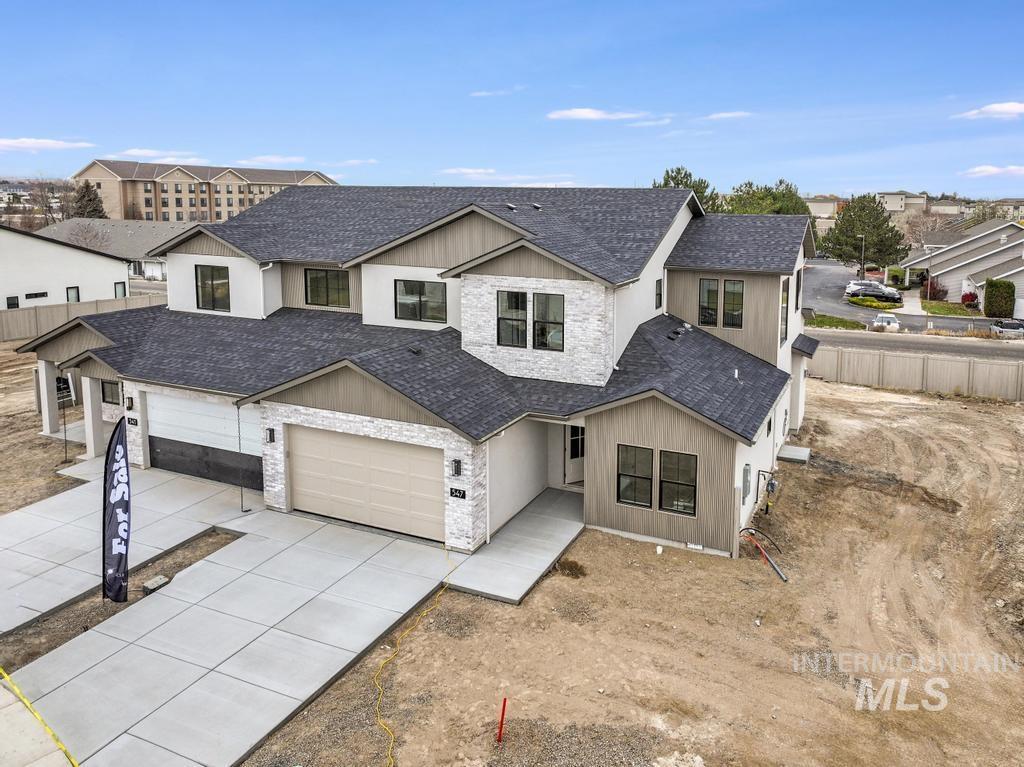 Modern farmhouse style home featuring roof with shingles, concrete driveway, stone siding, and a garage