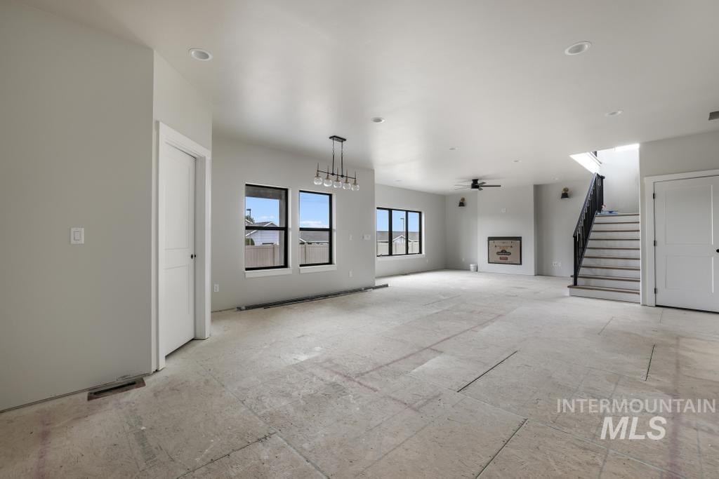 Unfurnished living room featuring stairs and a ceiling fan