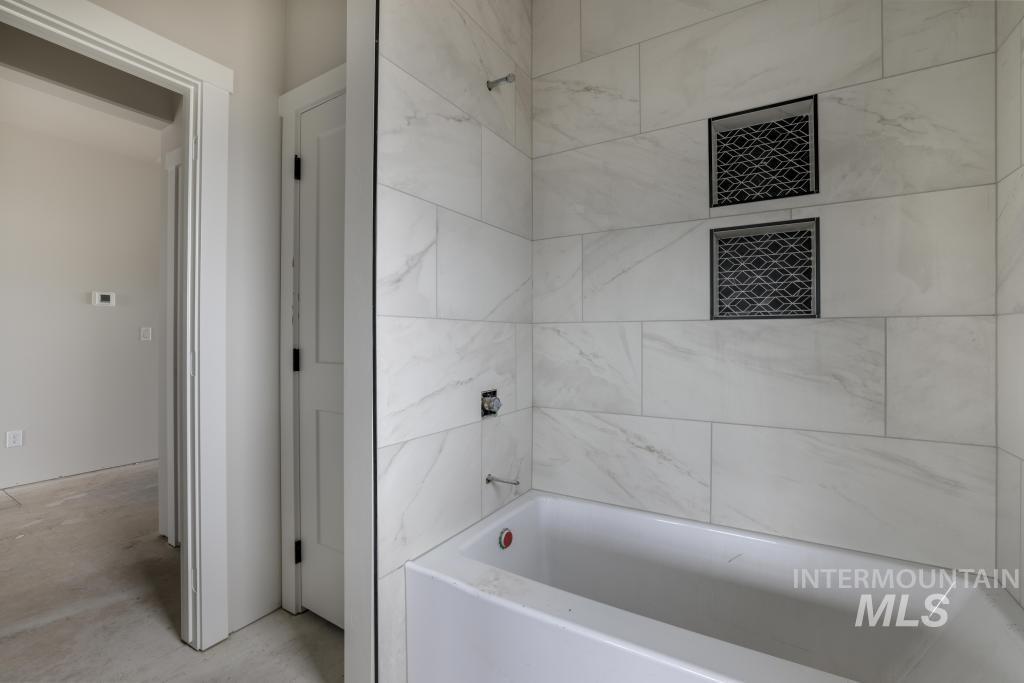 Bathroom featuring unfinished concrete floors and bathing tub / shower combination