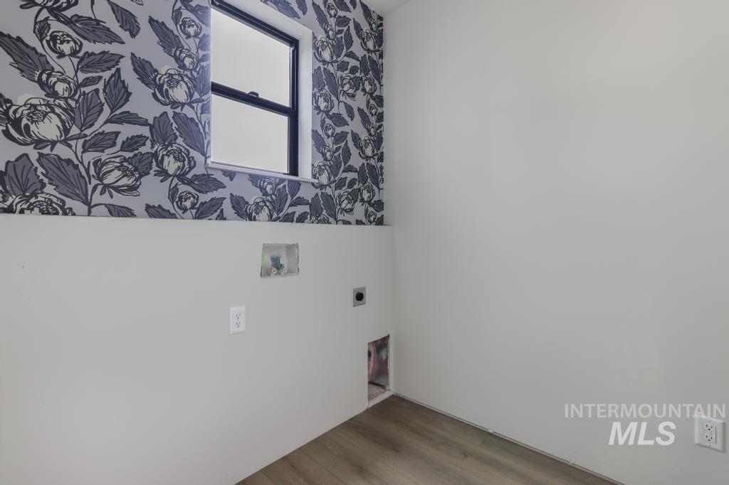 Laundry area featuring wood finished floors, hookup for a washing machine, electric dryer hookup, and wallpapered walls