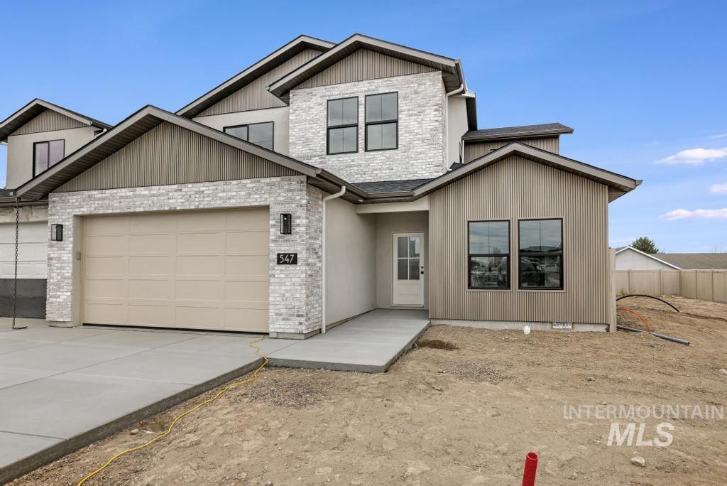View of front facade featuring driveway, a garage, and brick siding