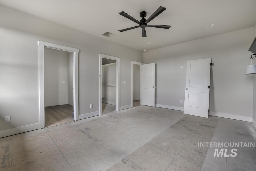Unfurnished bedroom with ceiling fan and a spacious closet