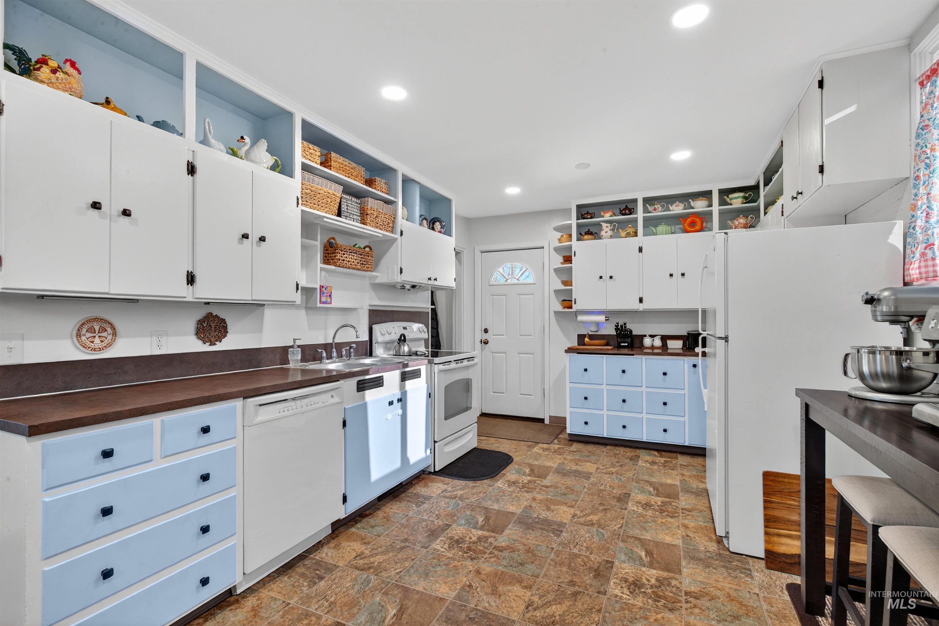 Kitchen featuring open shelves, white cabinetry, white appliances, stone finish flooring, and recessed lighting