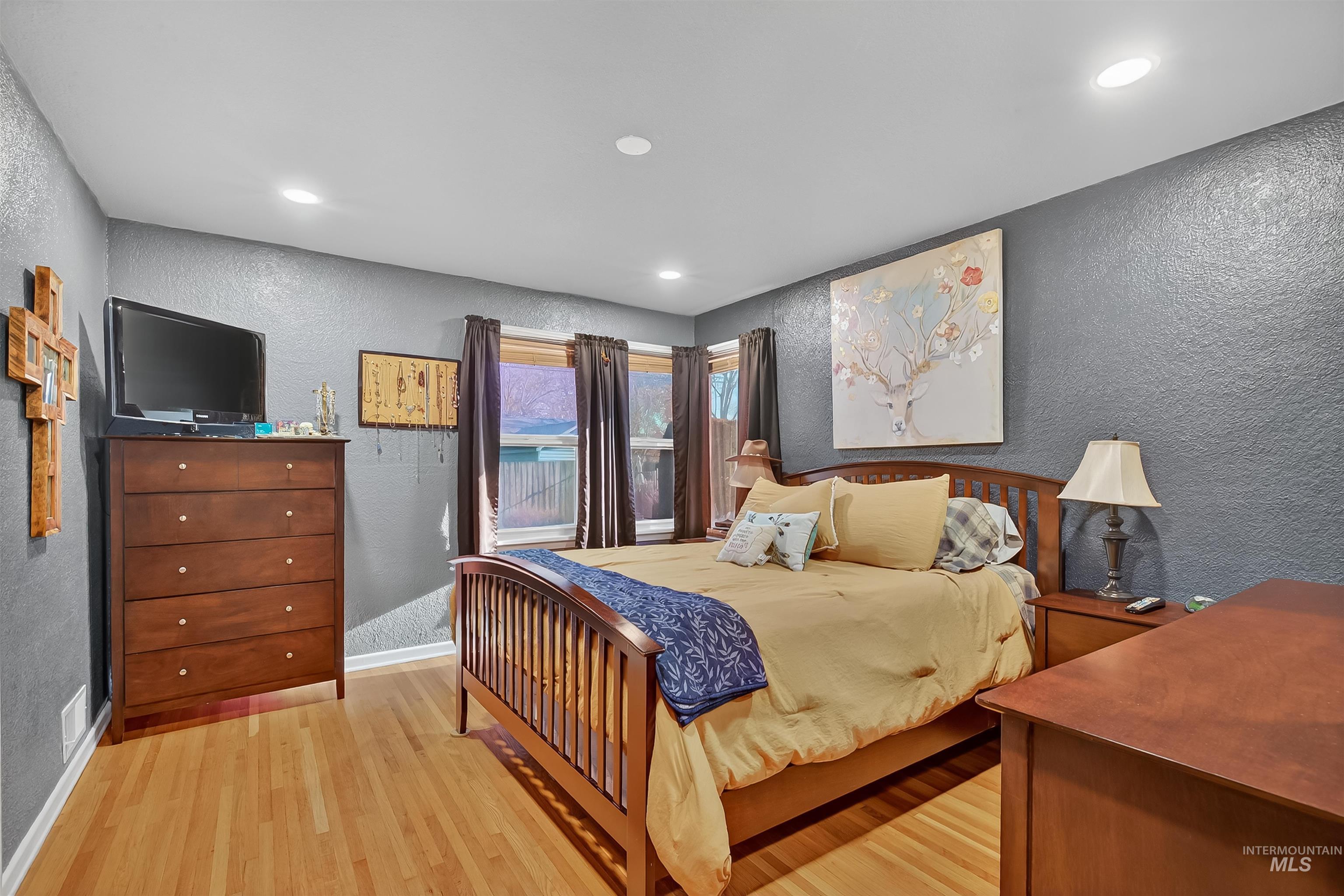 Bedroom with a textured wall, light wood finished floors, and recessed lighting