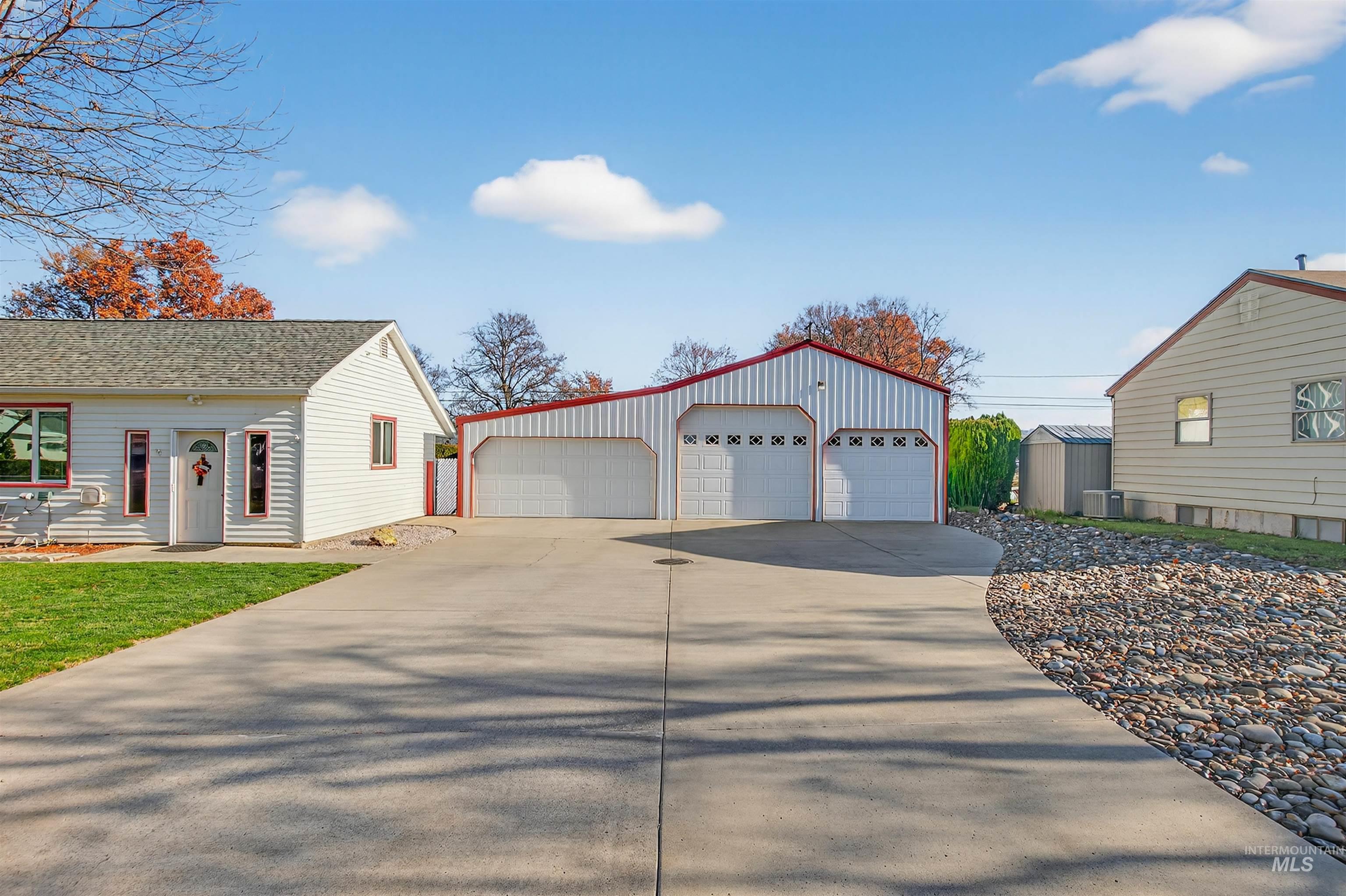 View of side of property with an outbuilding, a detached garage, and a shingled roof